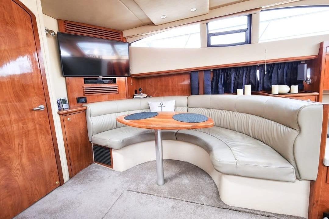 Luxurious 2006 Cruisers Yachts 385 Motoryacht interior with curved seating and TV.