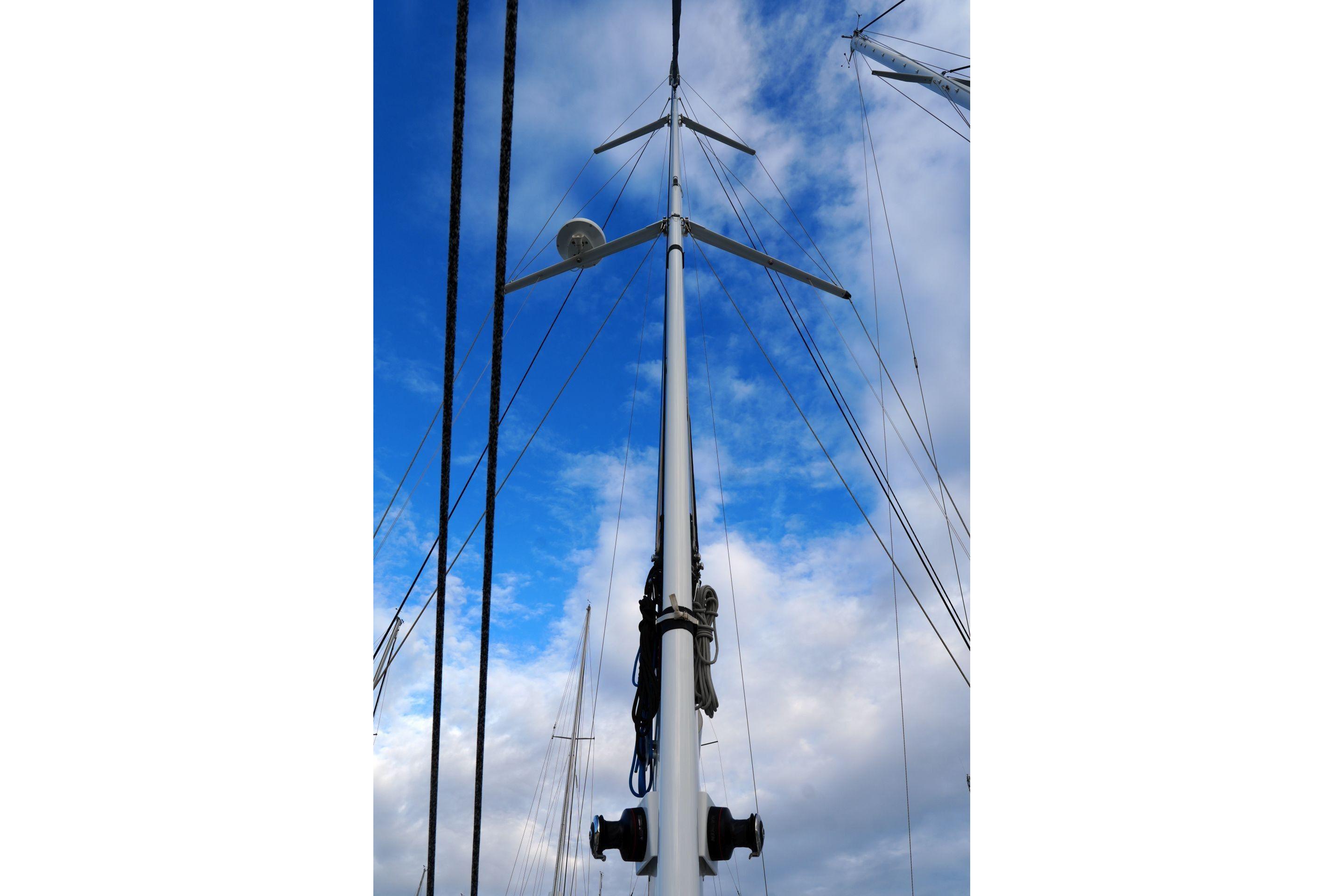 Mast of 2023 Amel 50 sailboat against a blue sky with clouds.