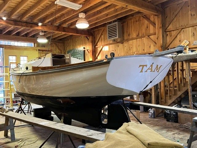 A 1973 Talman Yacht Menemsha-24 is on a stand in a wooden workshop.