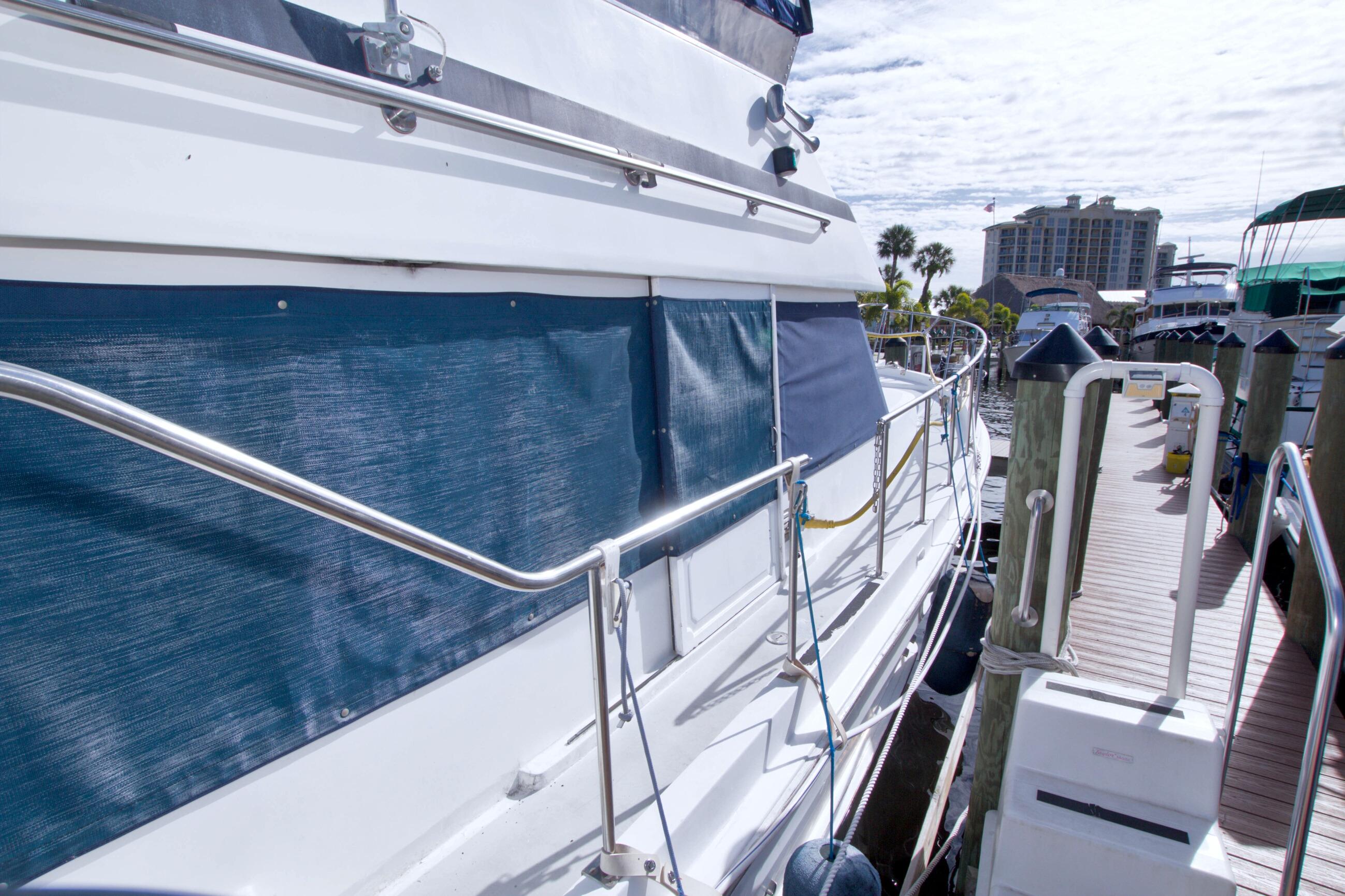 1984 Present Yachts 42 Sundeck docked, featuring blue canvas and stainless steel railings.