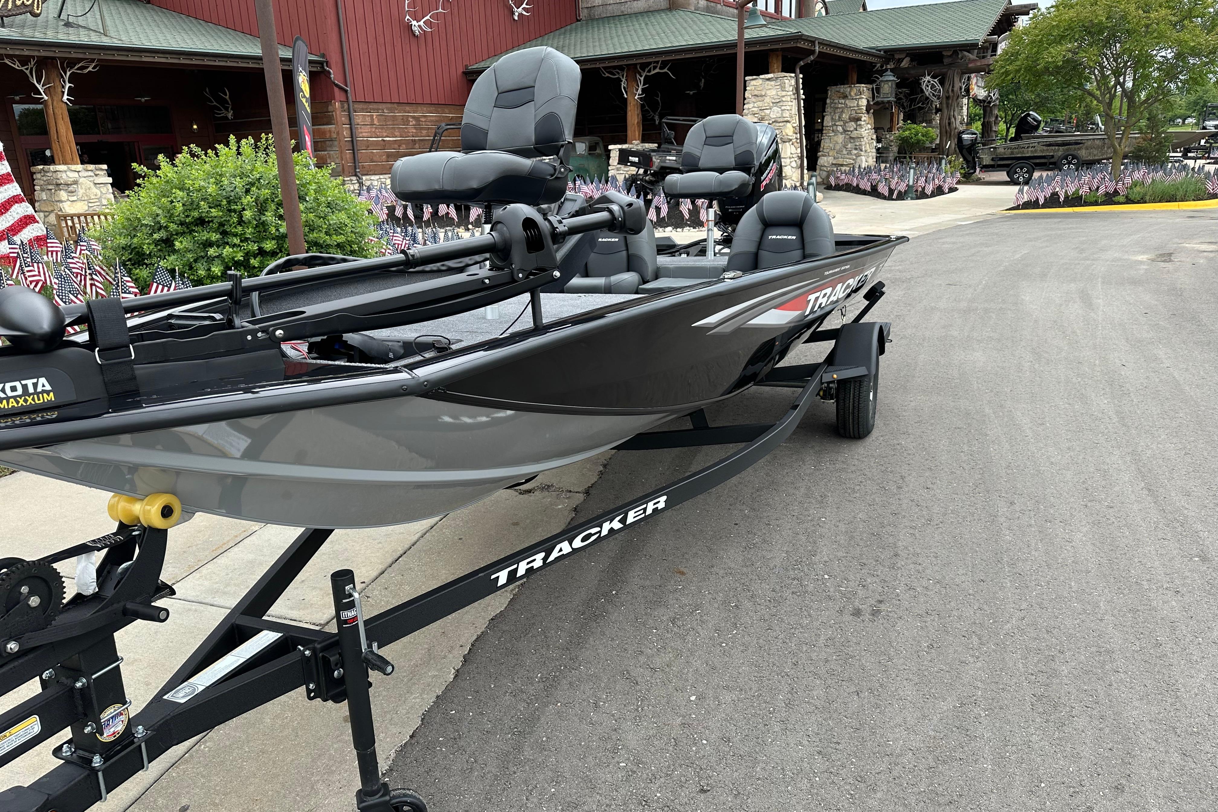 2026 Tracker Pro Team 190 boat on trailer, parked near a building with flags.