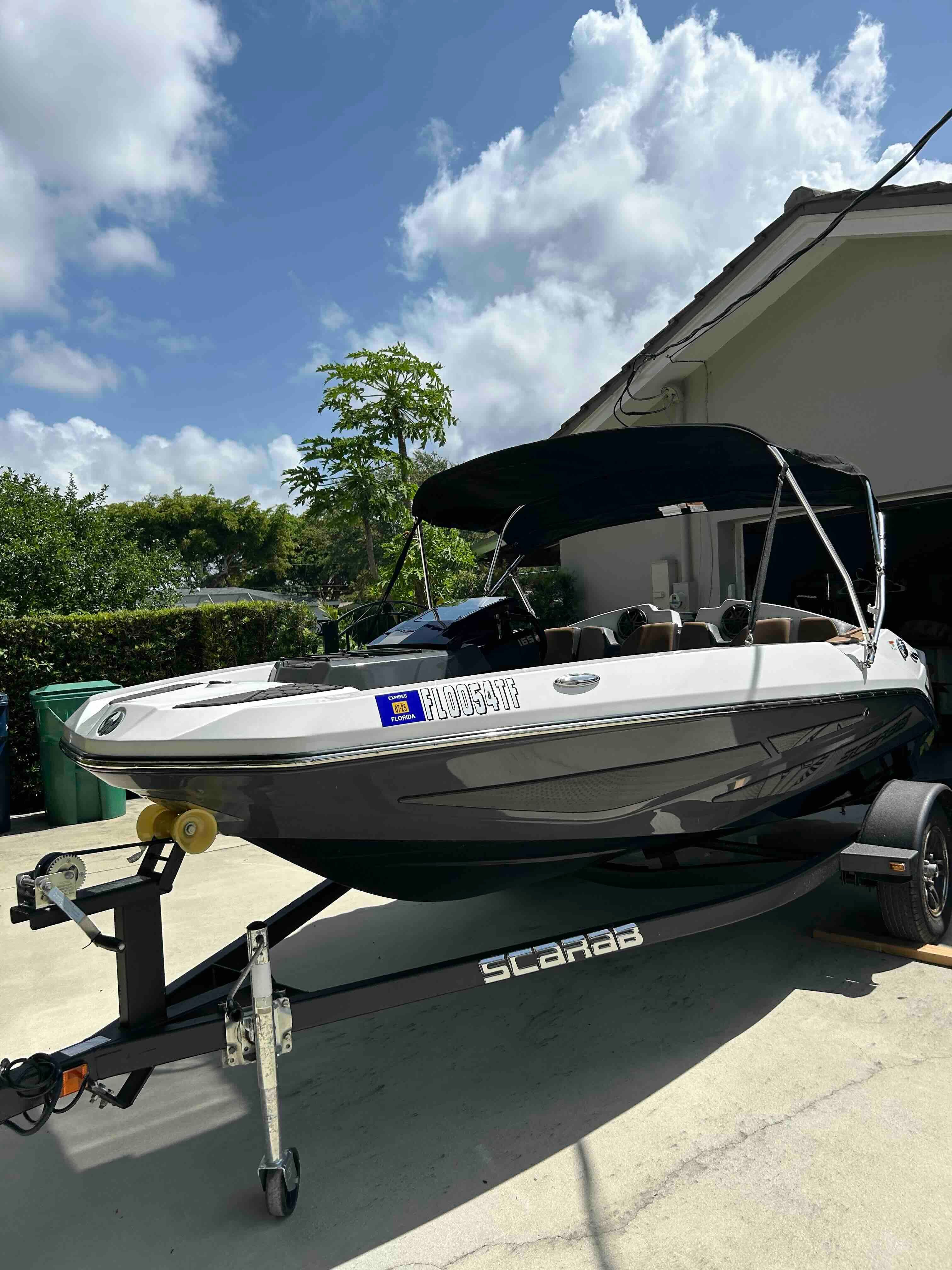 A 2022 Scarab 165 ID boat on a trailer in a driveway.