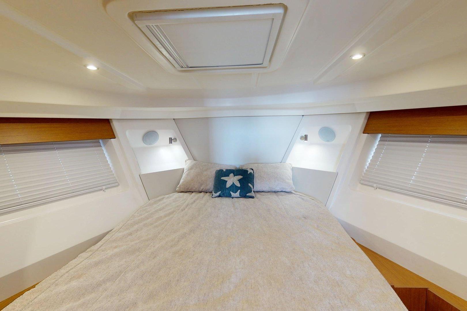 Interior cabin of 2021 Beneteau Swift Trawler 35 with cozy bed and starfish pillow.