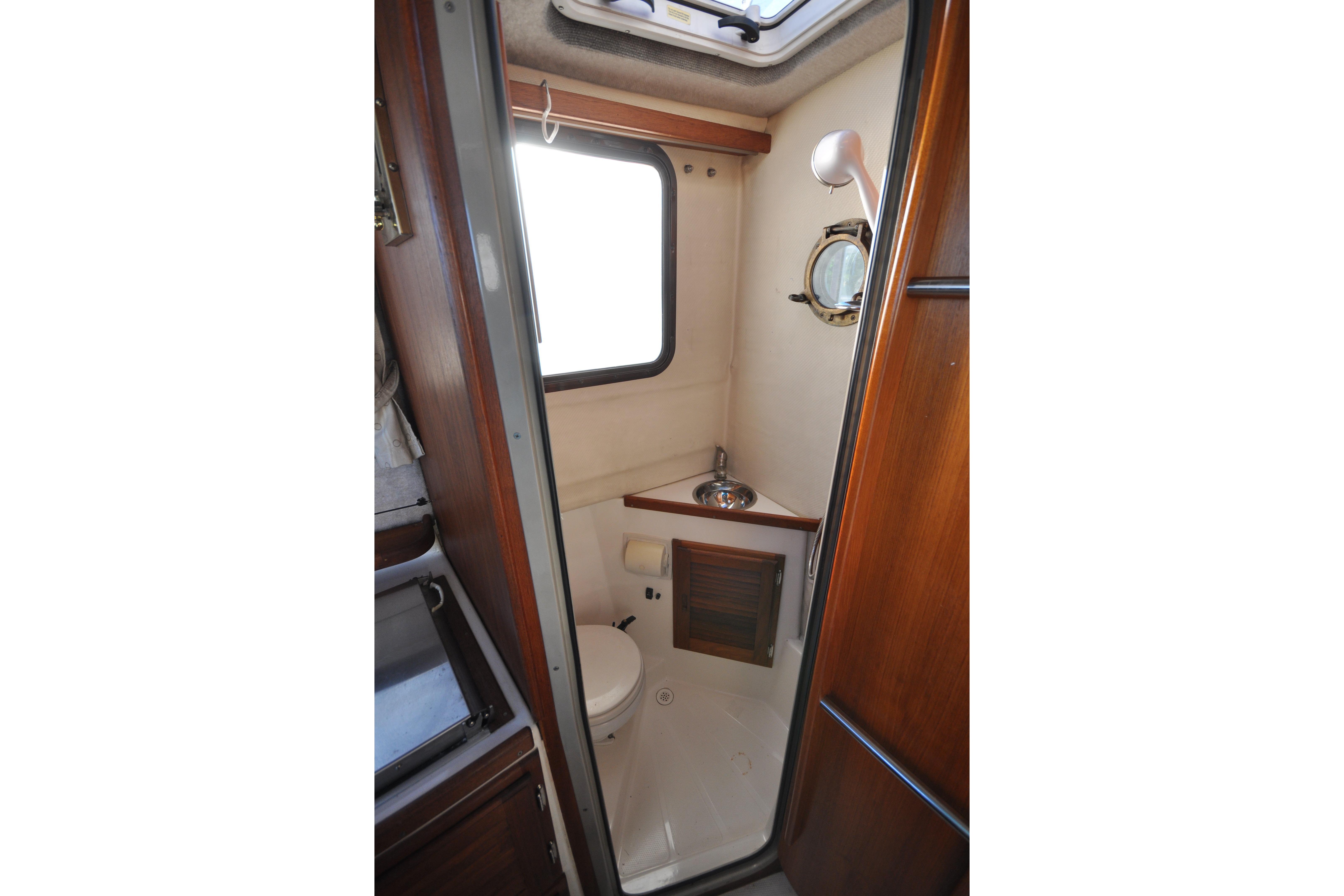 2007 Ranger Tugs R-25 boat bathroom with sink, toilet, and porthole window.