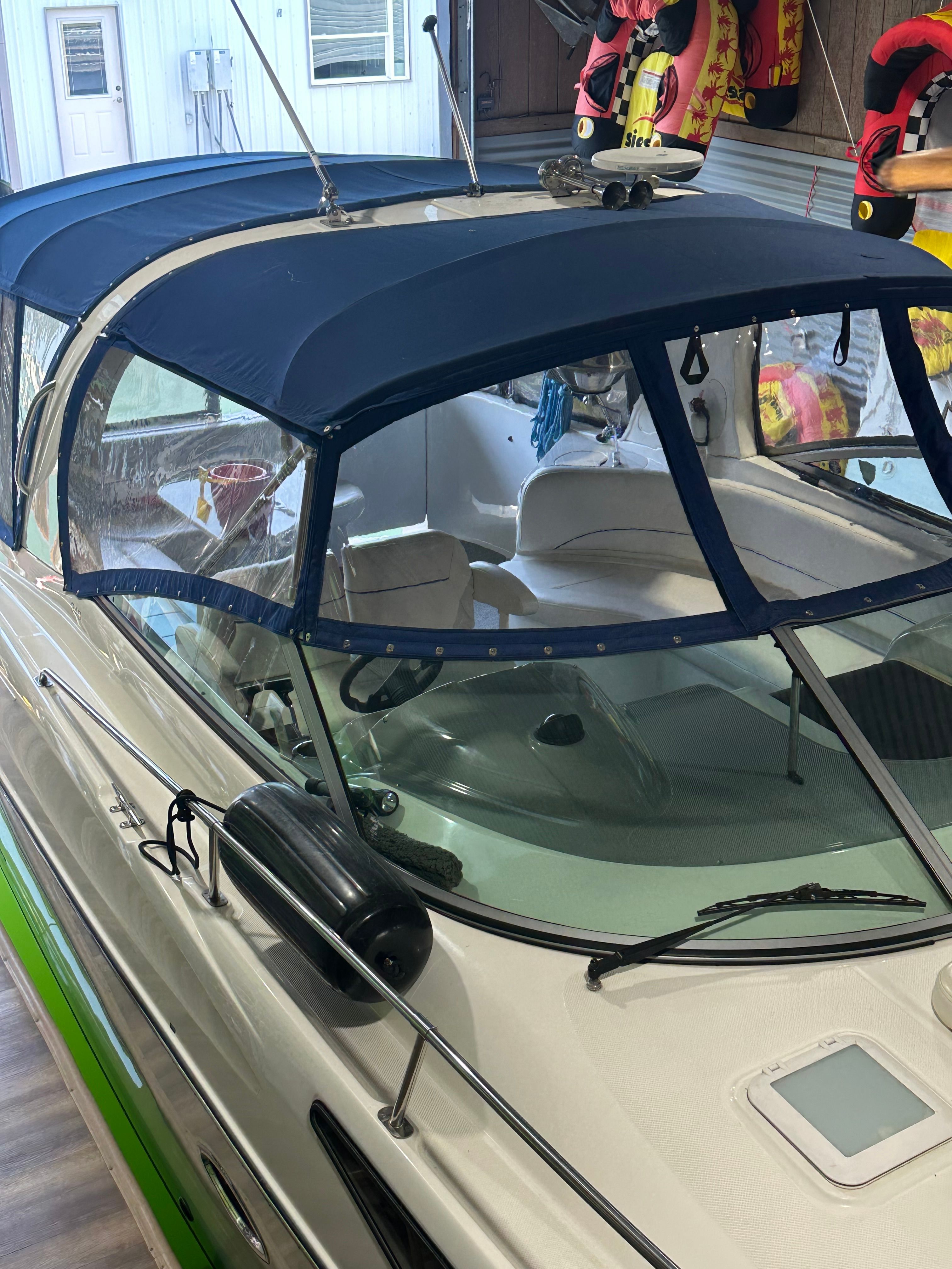 2008 Bayliner 340 boat with blue canopy in a garage.