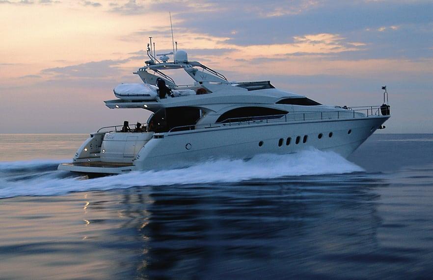Luxurious 2008 Dominator 680 yacht cruising at sunset on calm waters.