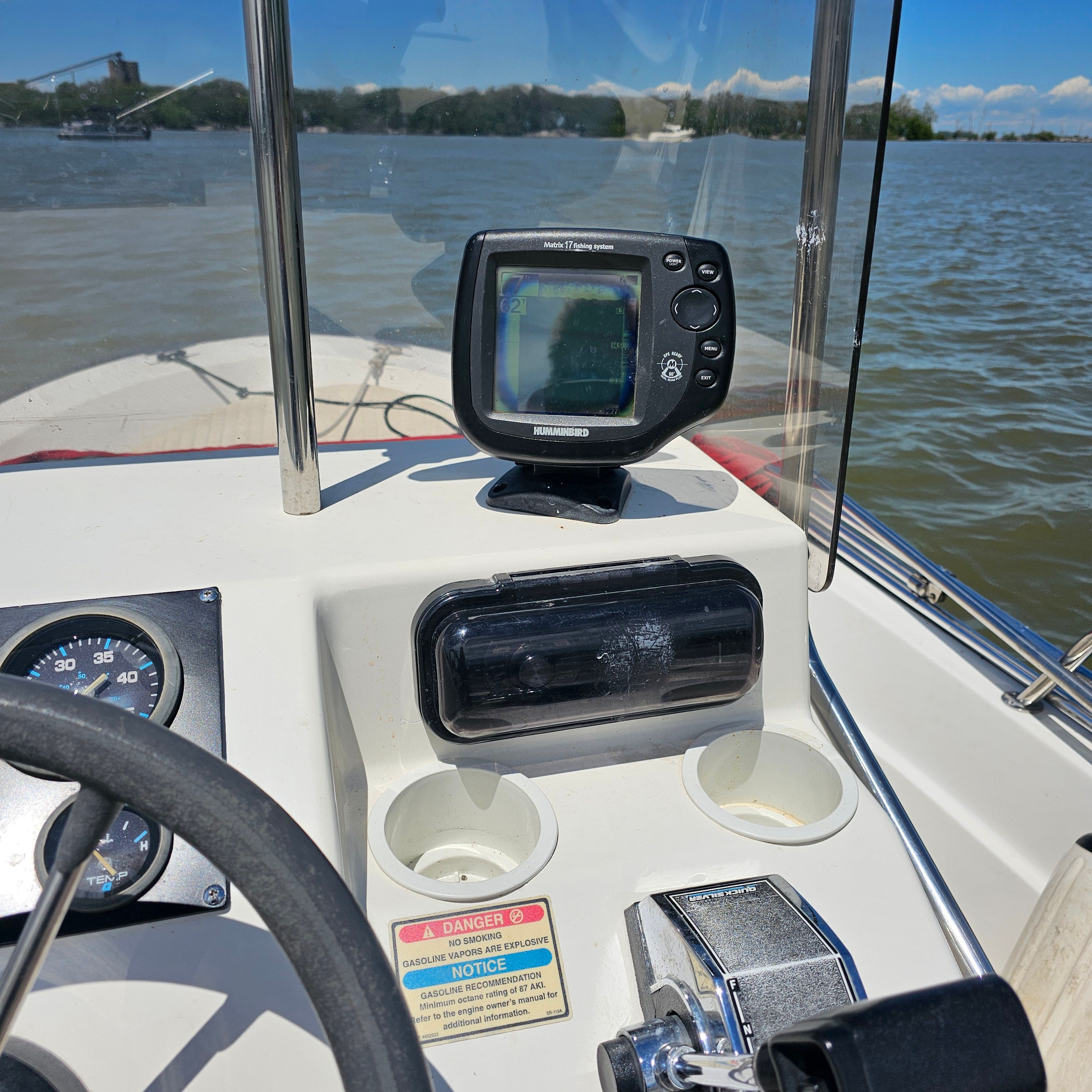 The cockpit of a boat with a fish finder and control instruments.