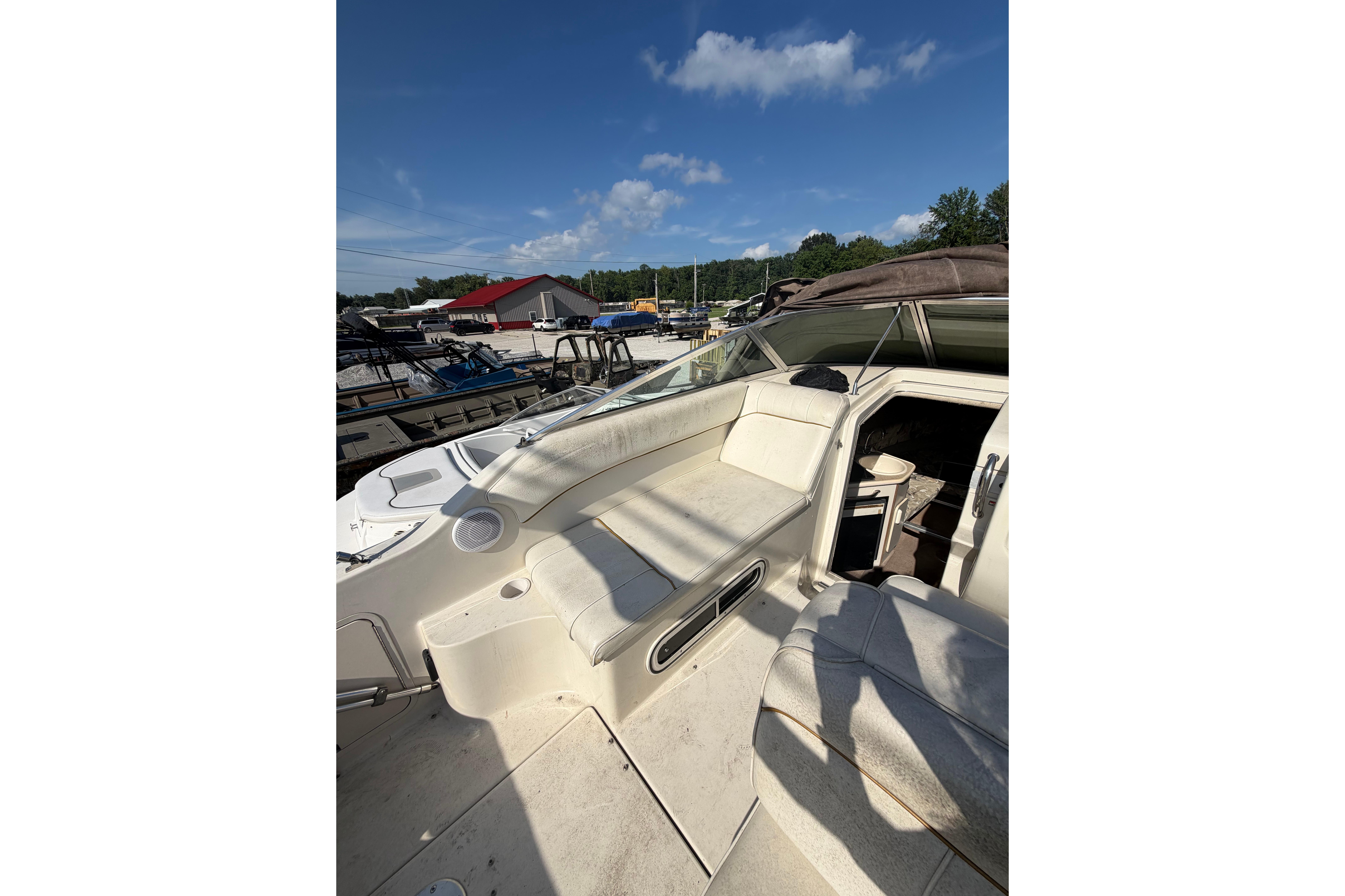 1999 Sea Ray 240 Sundancer boat interior with seating and cabin under clear blue sky.