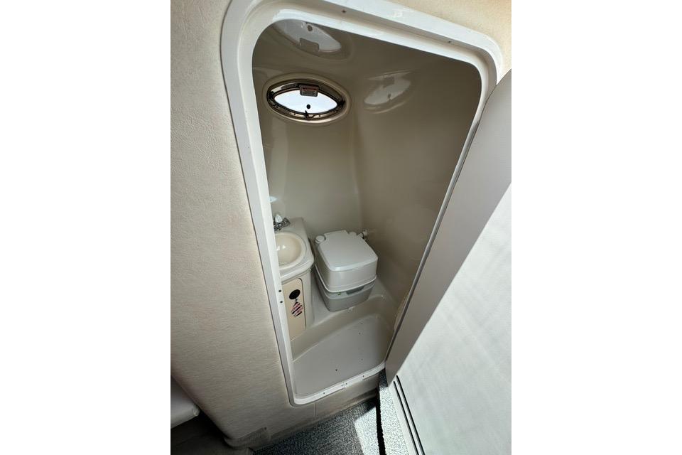 Compact bathroom in 2004 Sea Ray 240 Sundancer boat with toilet and sink.