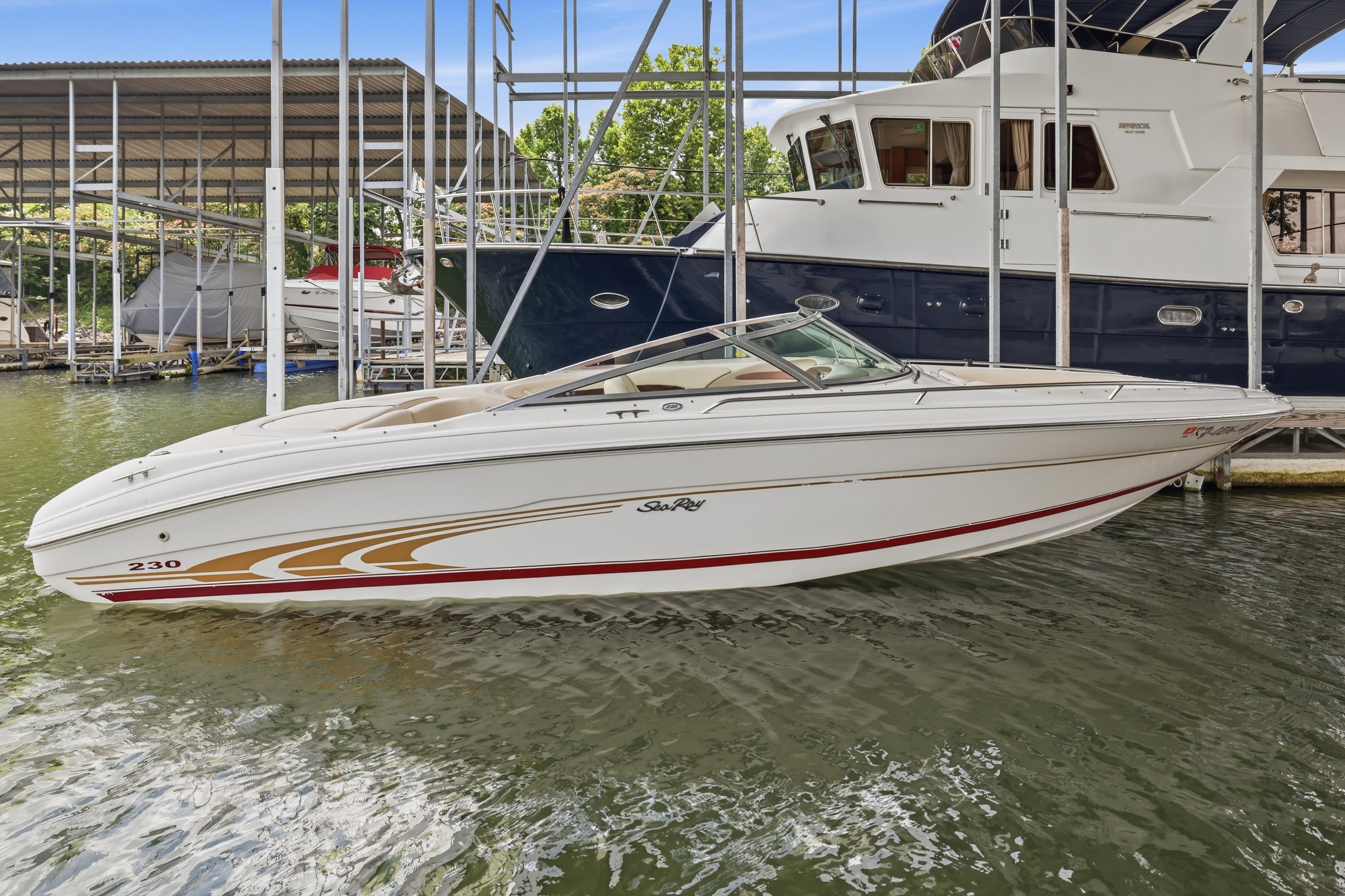 1997 Sea Ray 230 Signature boat docked at marina, featuring sleek white design and gold accents.
