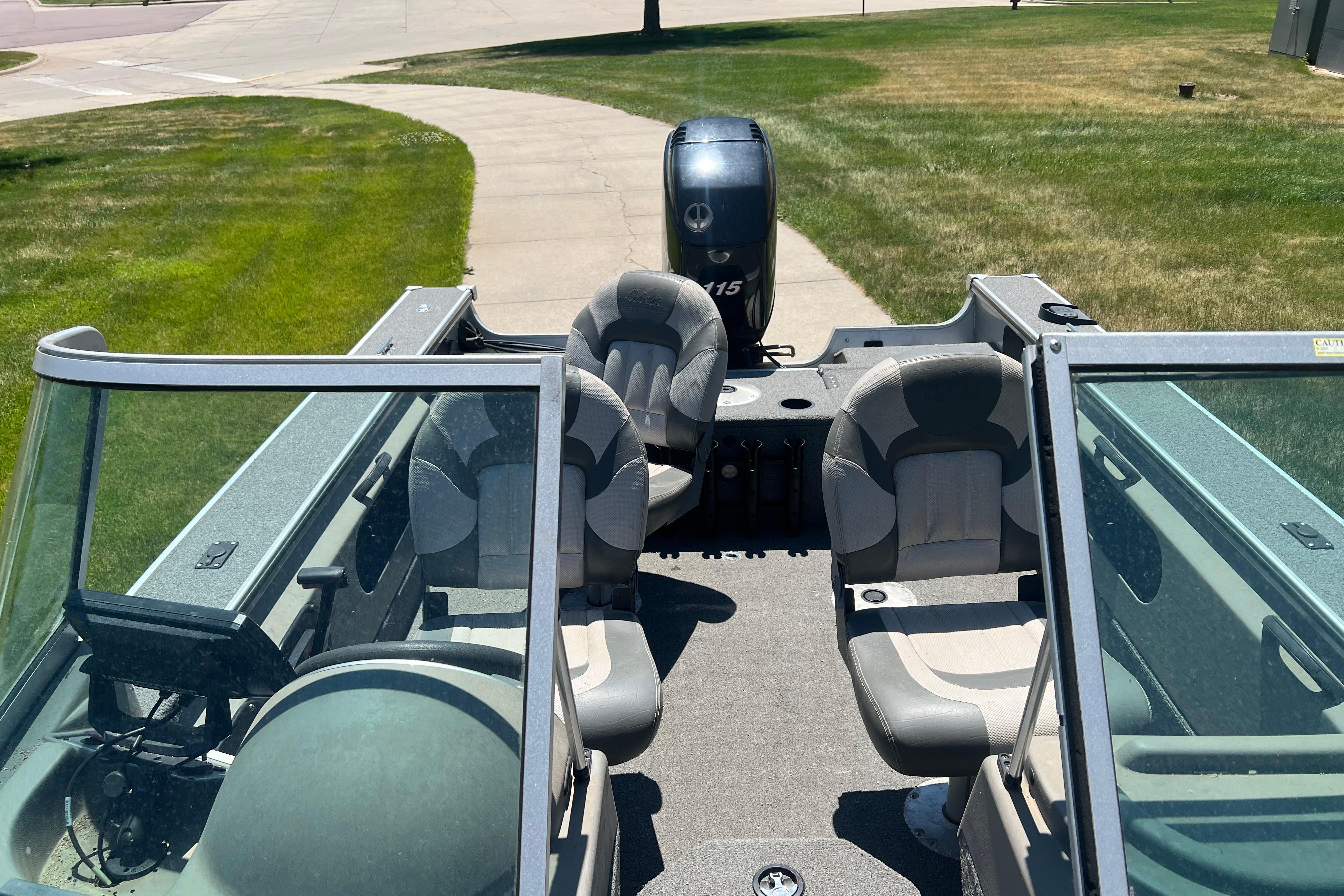 2010 Alumacraft Dominator 165 Sport boat with seating and outboard motor, parked on grass.