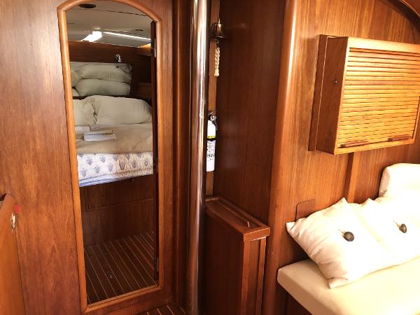 Interior of 2001 Jeanneau 45.2 yacht with wooden finish and cozy bedding.