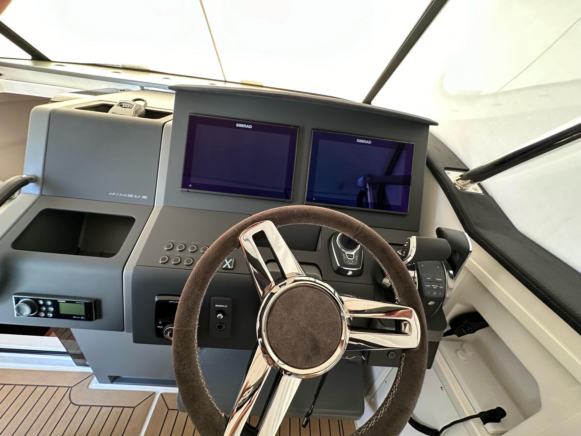 Cockpit of 2023 Nimbus T11 boat with dual screens and modern steering wheel.