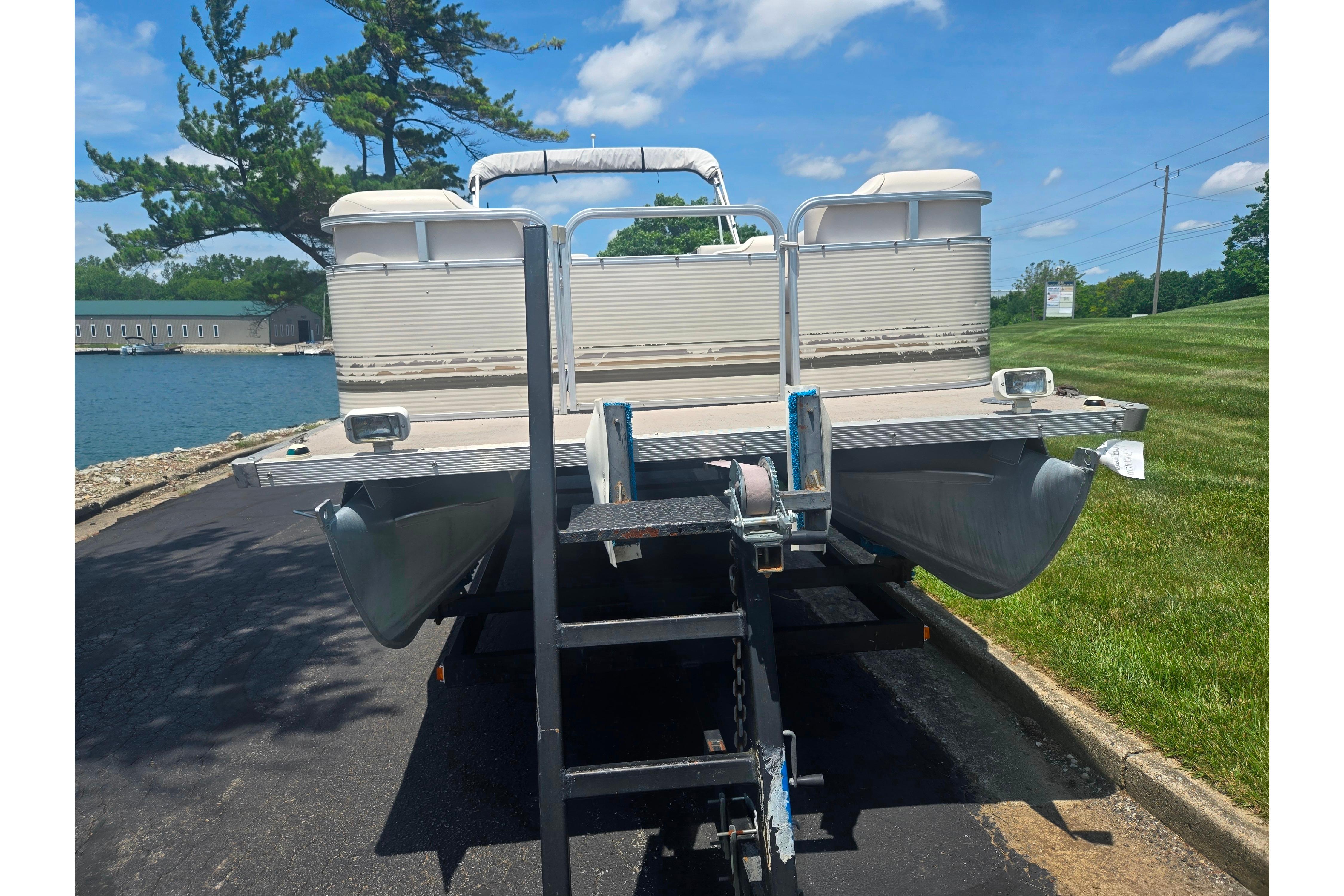 2000 Sylvan 824 Elite Cruise pontoon boat on trailer by lakeside.