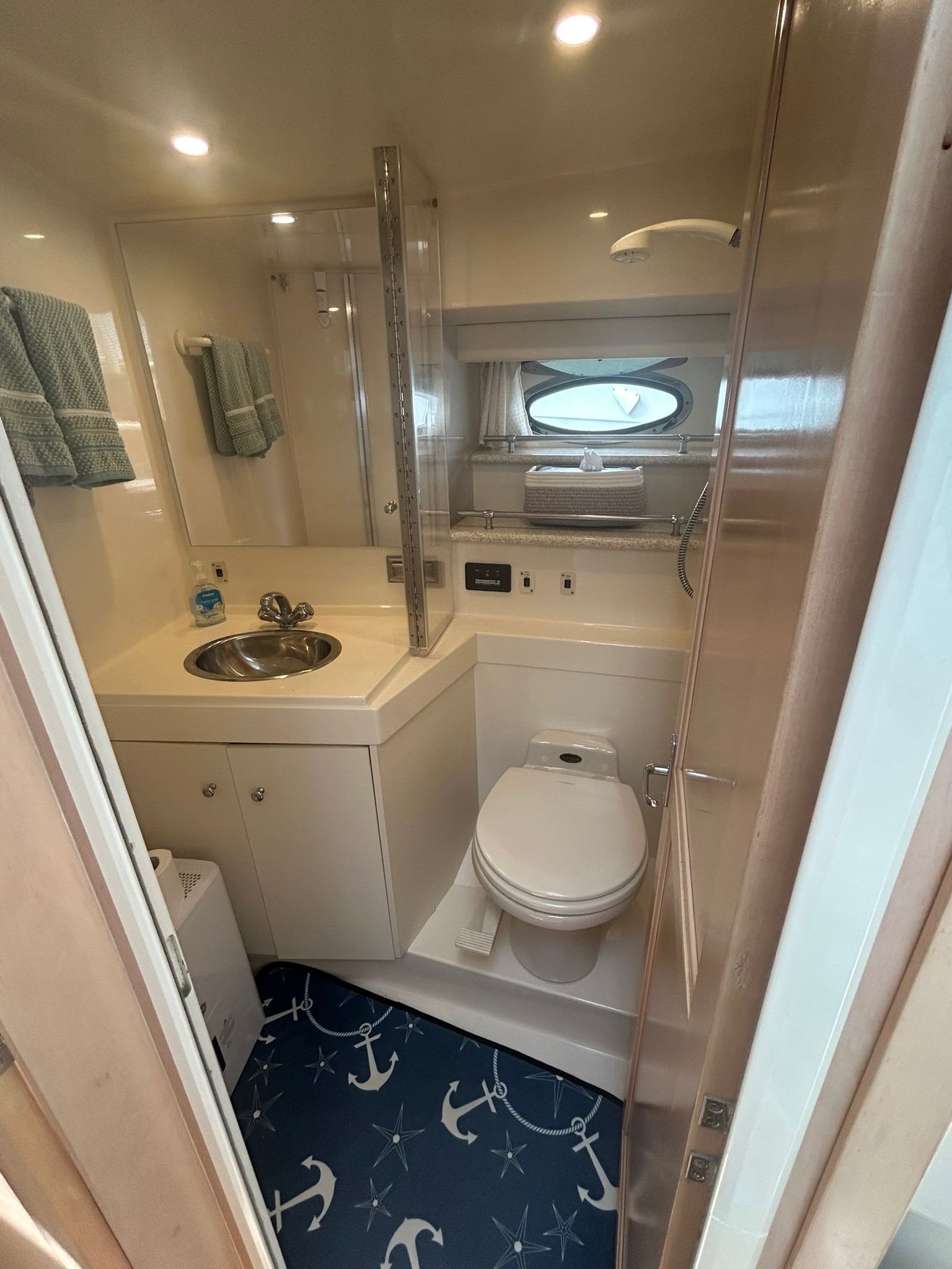 Carver 356 yacht bathroom with anchor-themed floor and porthole.
