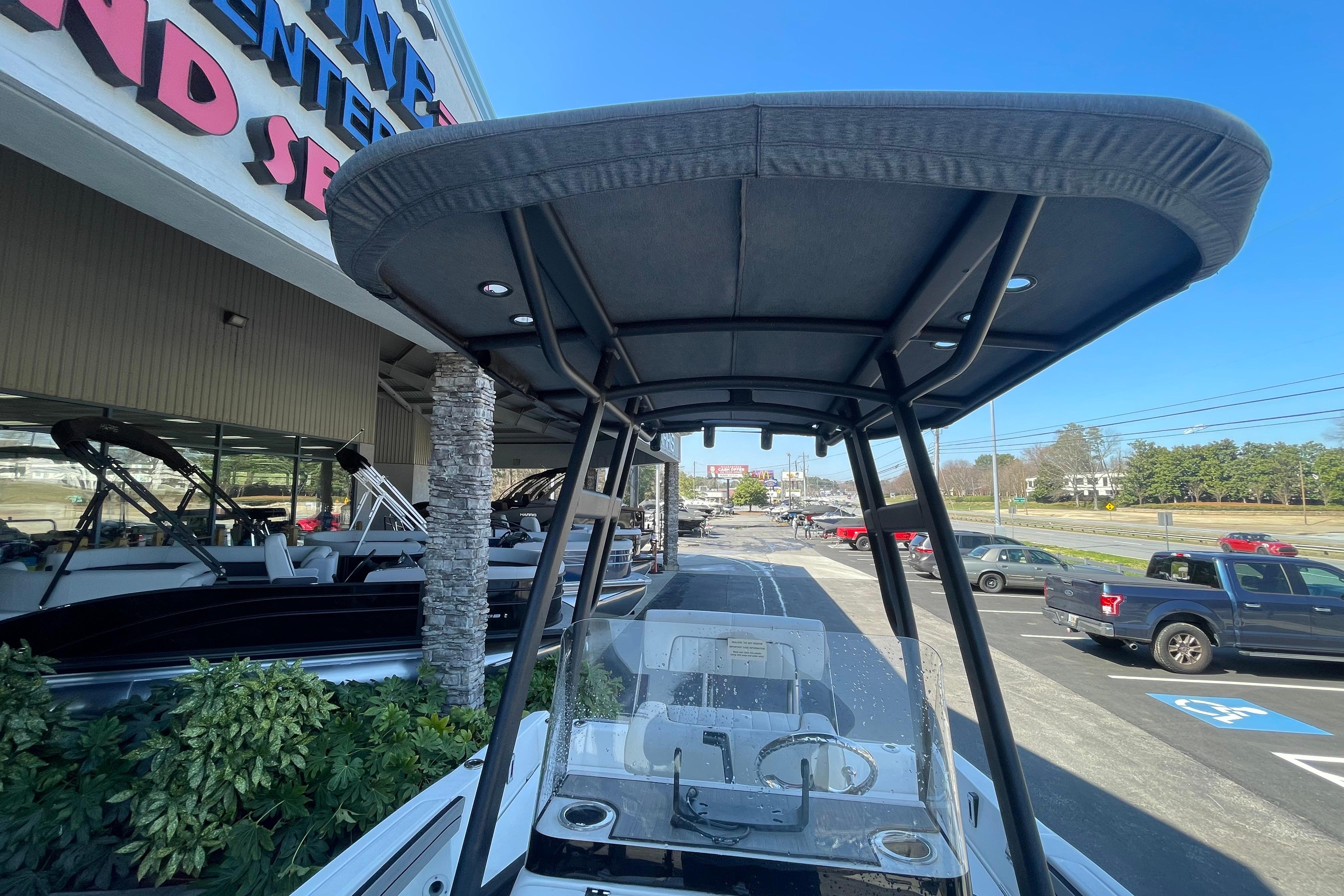 2021 Yamaha Boats 195 FSH Sport displayed at a dealership, featuring a T-top canopy.