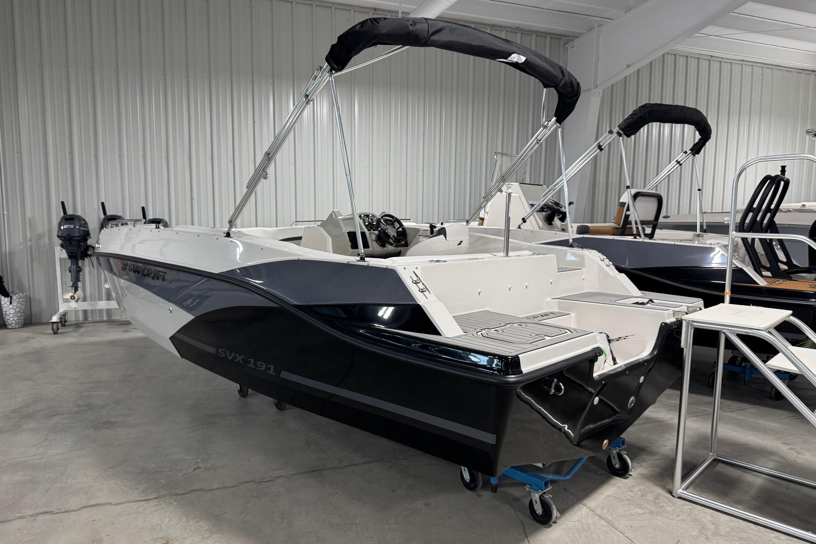 2026 Starcraft SVX 191 OB boat in showroom, sleek design, black and white color scheme.