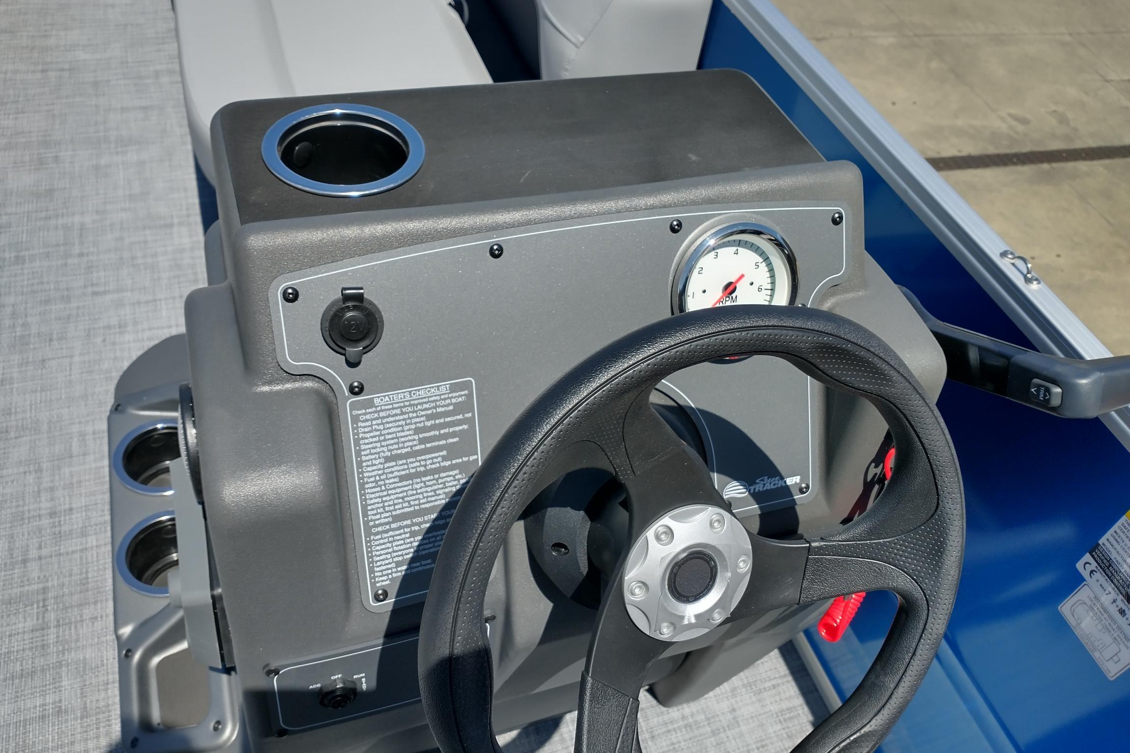 Steering console of 2026 Sun Tracker Party Barge 16 DLX with RPM gauge and cup holder.