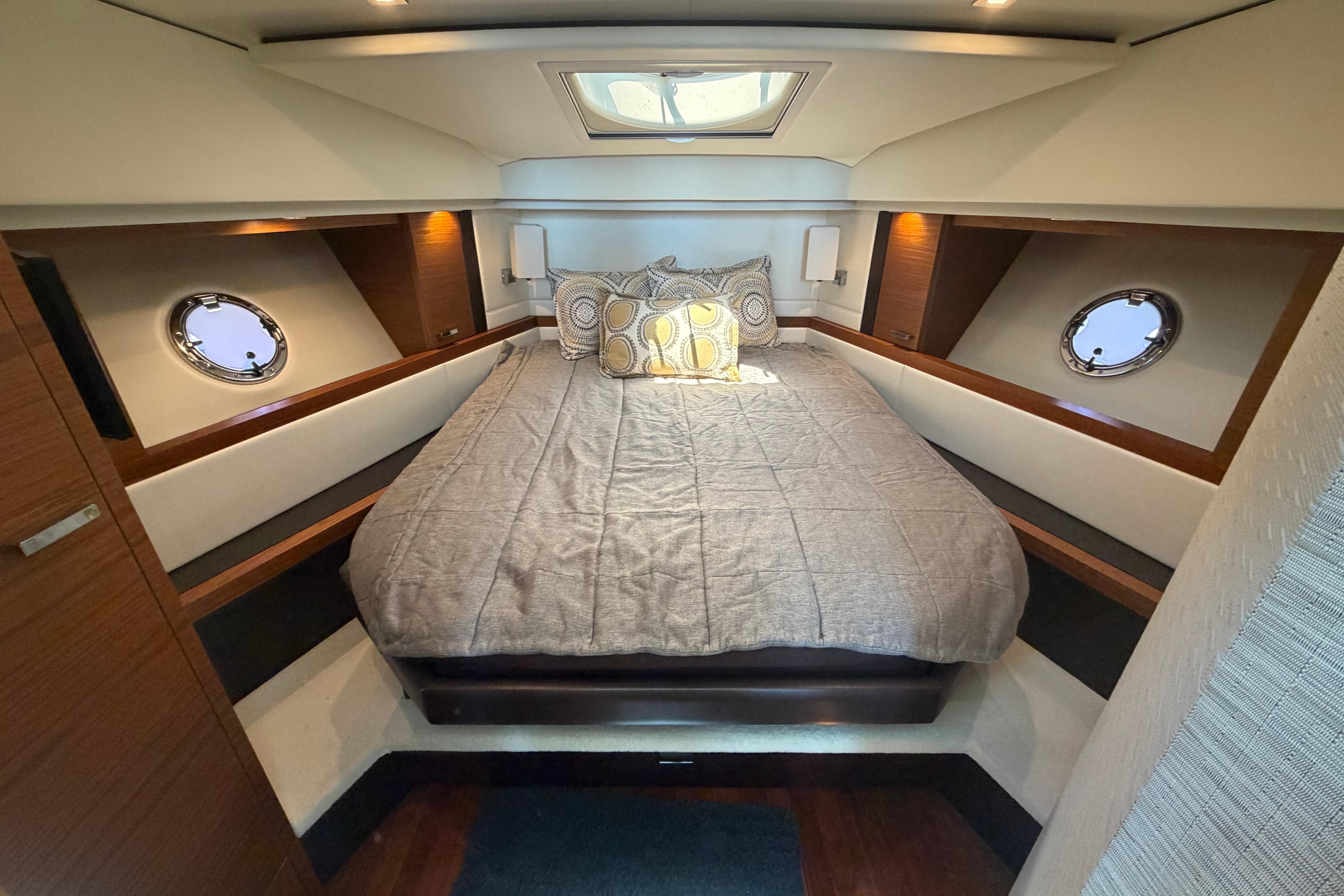Luxurious cabin interior of 2016 Tiara Yachts C39 Coupe with cozy bed and porthole windows.