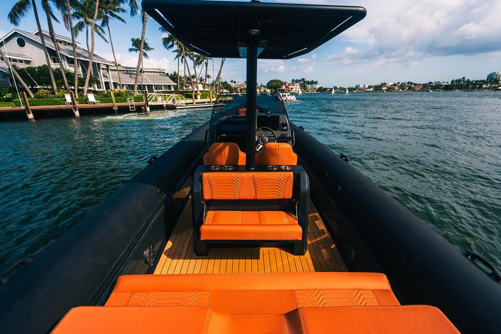Luxury Onda Magna 2025 boat with orange seating, cruising near palm-lined waterfront homes.