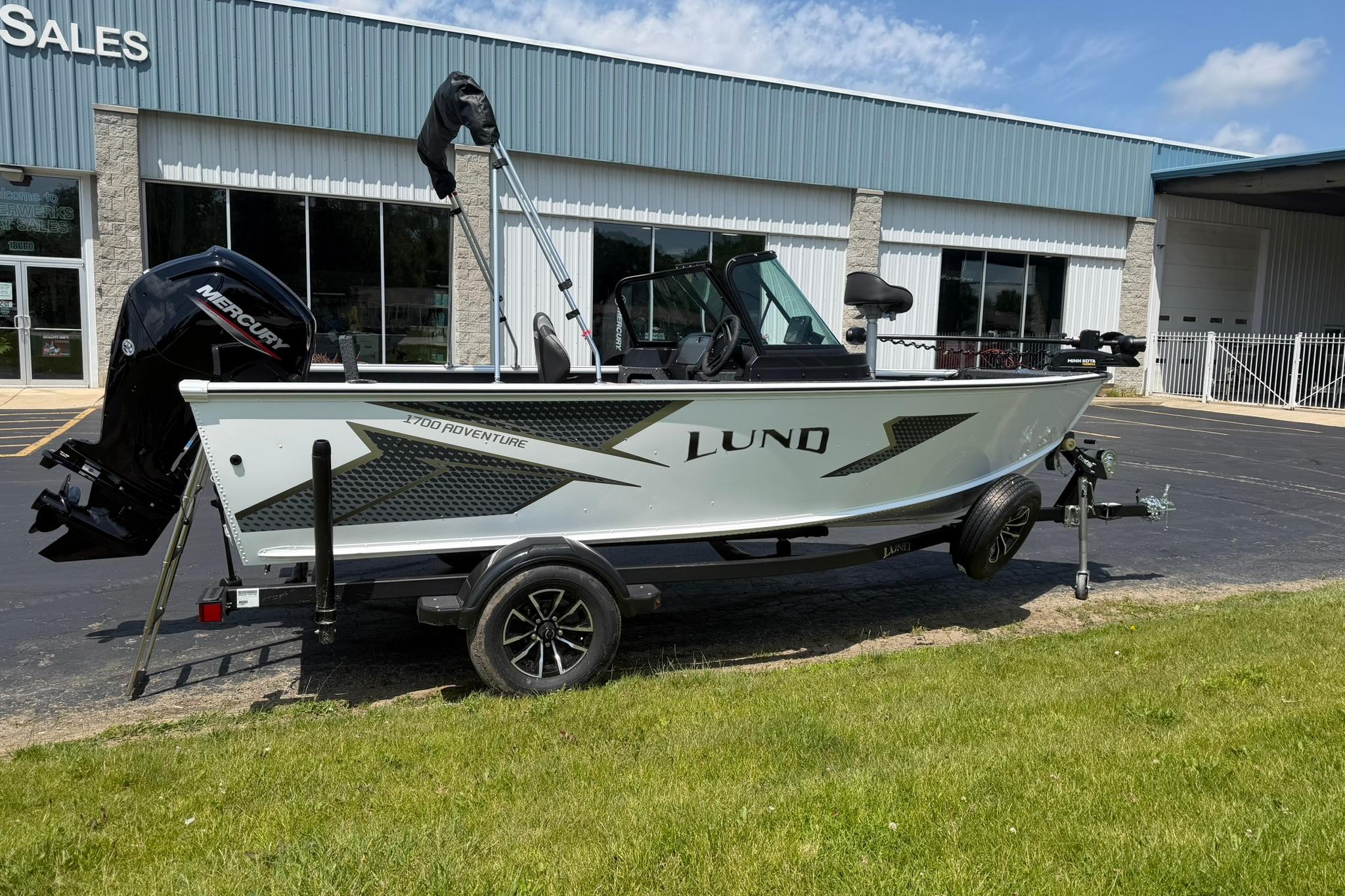 2027 Lund 1675 Adventure Sport boat on trailer, parked outside a sales building.