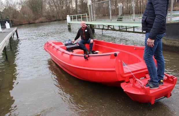Red 2025 Whaly 500R Pro boat on water near dock, with two people aboard.