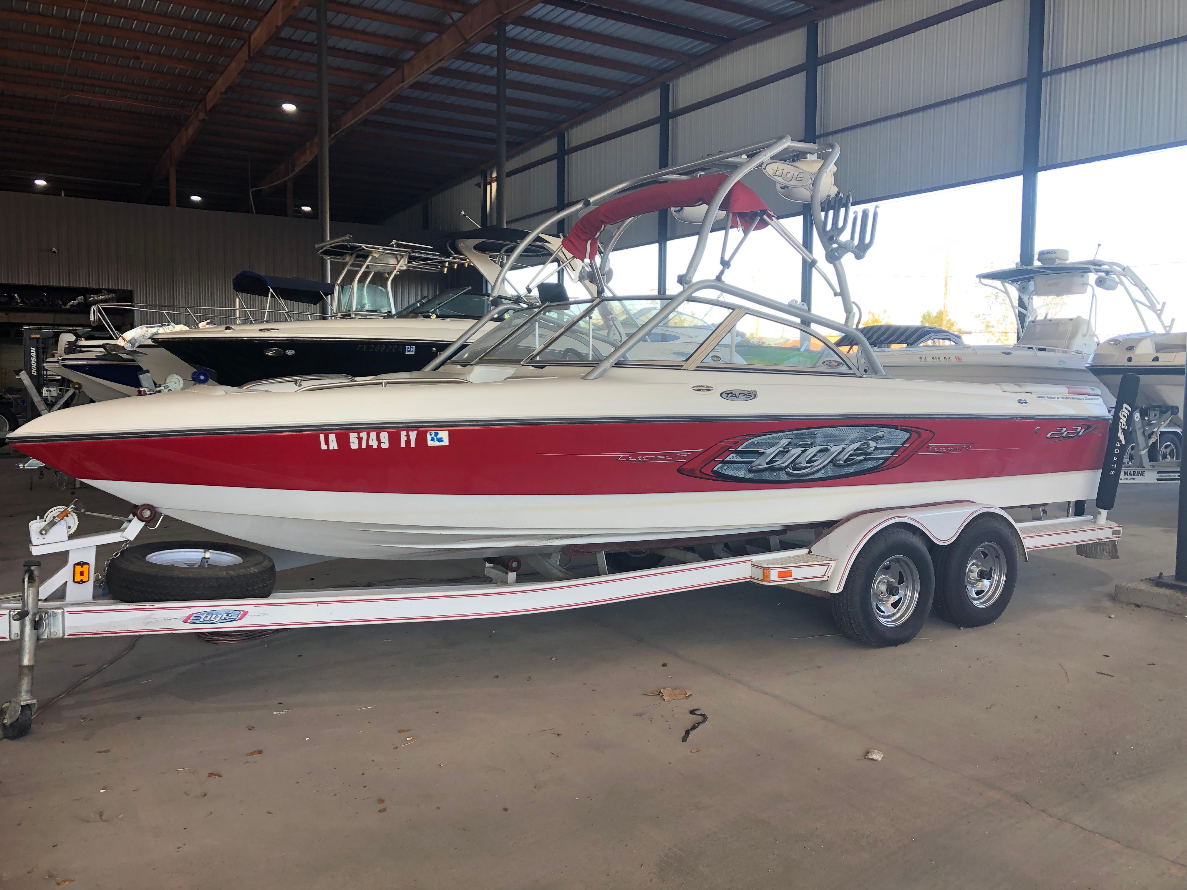 2004 Tigé 22I TYPE R boat in storage, red and white, on a trailer.