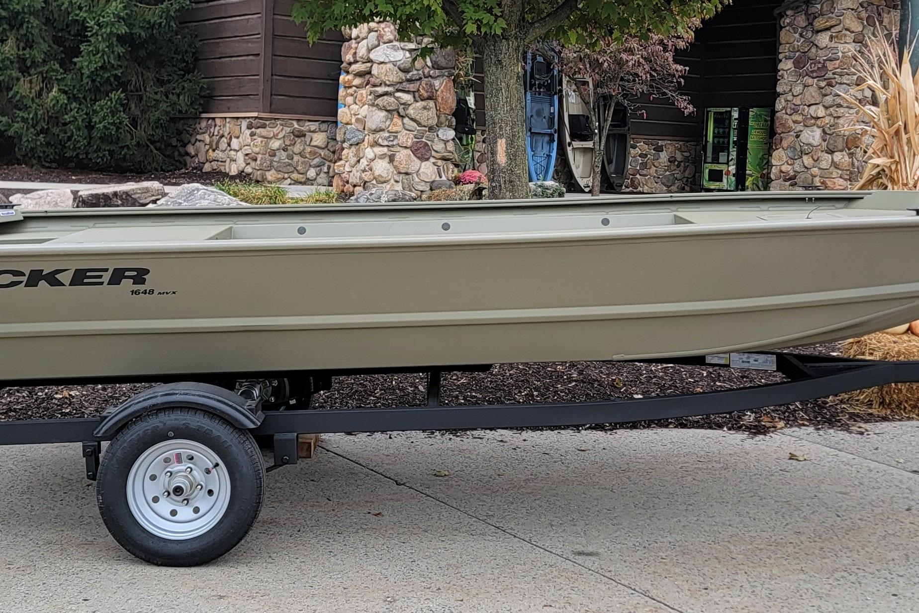 2026 Tracker Grizzly 1648 Utility boat on trailer, parked outdoors near stone building.