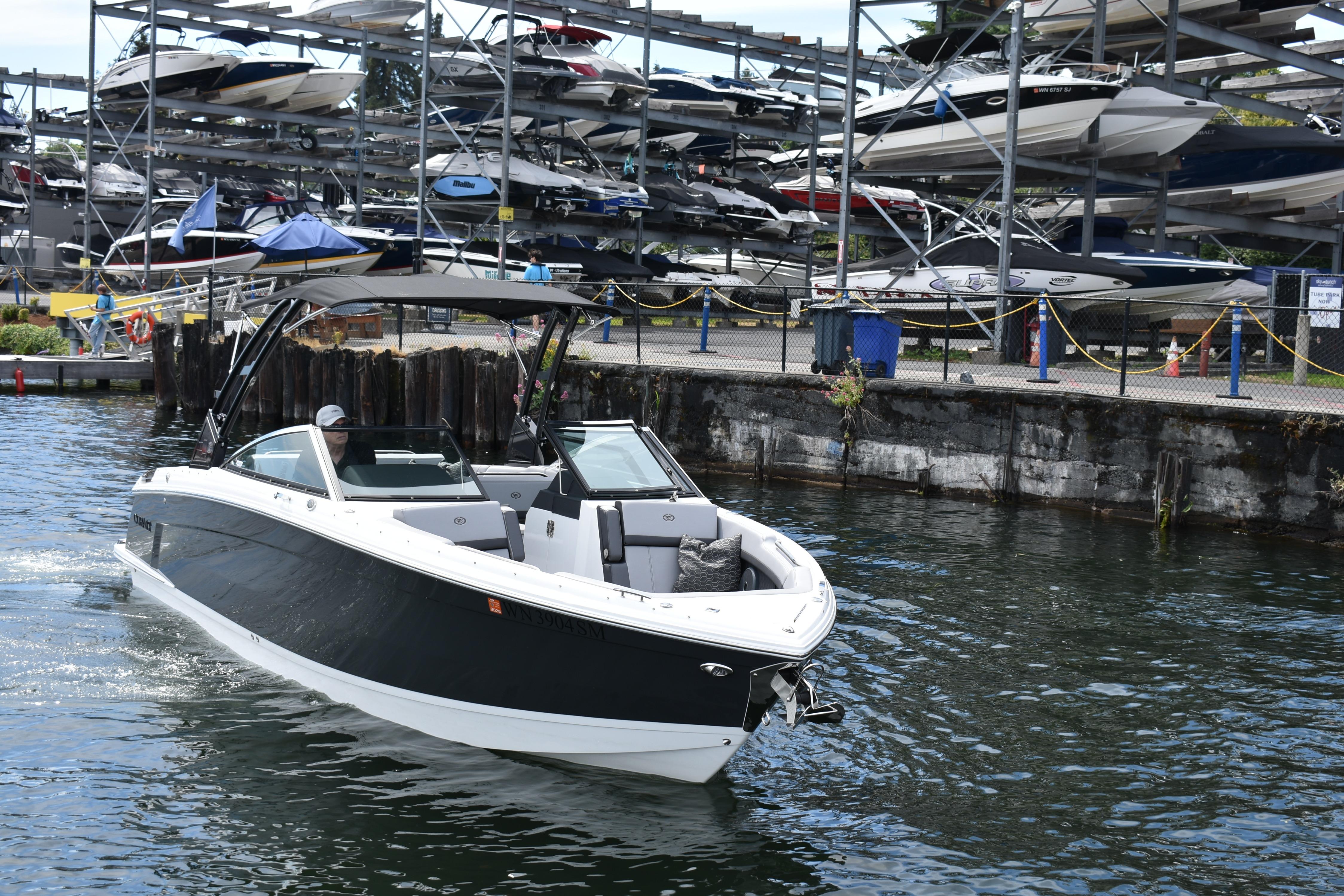 2023 Cobalt R8 boat cruising near a marina with stacked boats in the background.