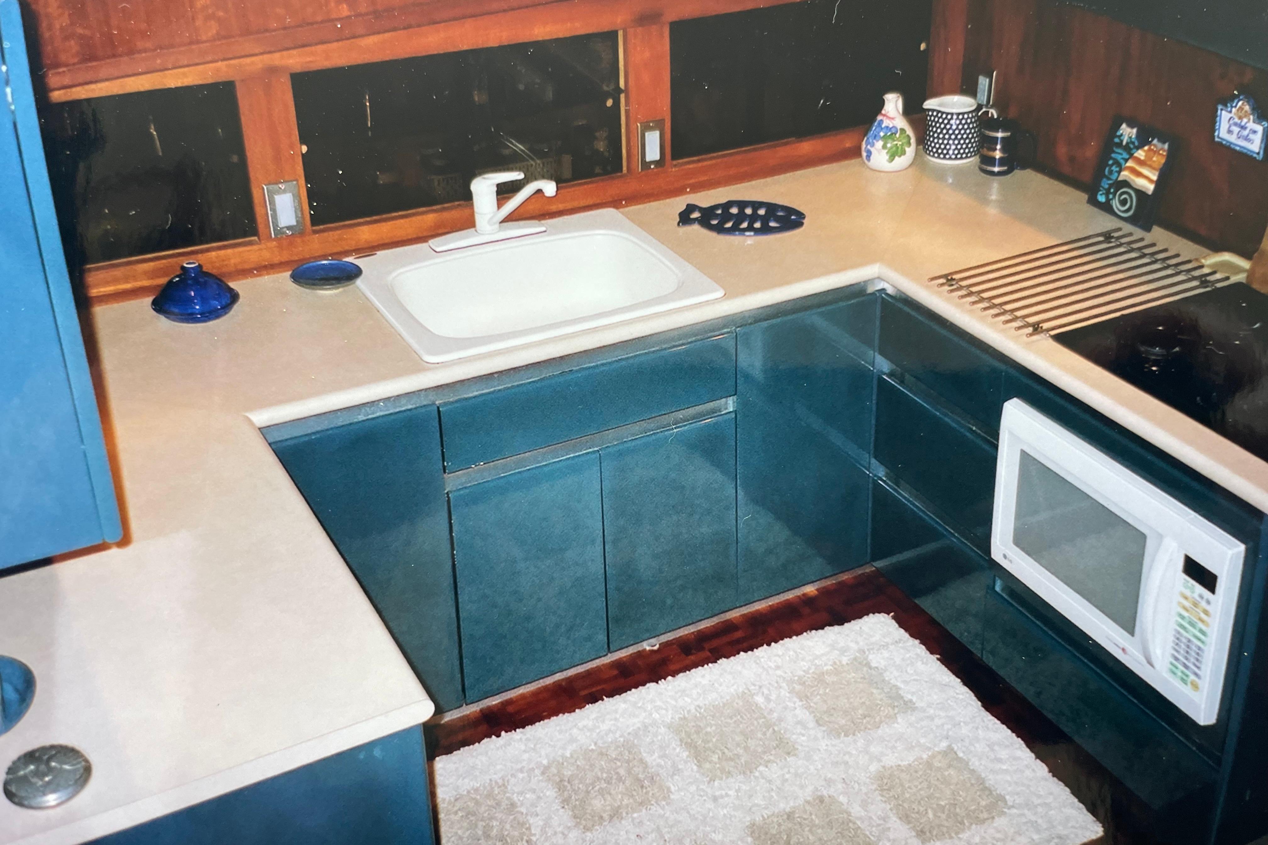 1973 Hatteras 58 Yacht Fisherman kitchen with blue cabinets, sink, and microwave.