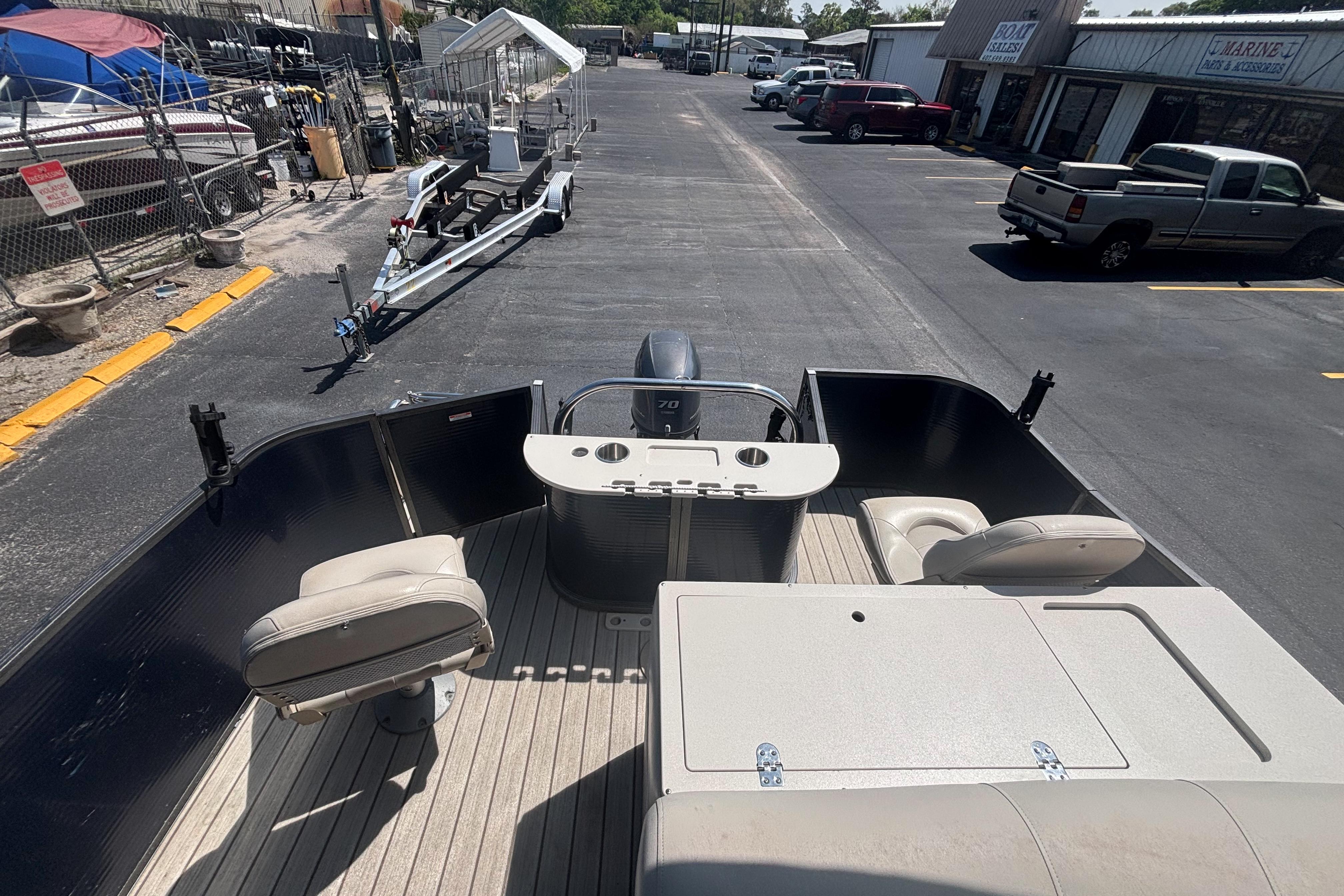 2015 Manitou 20 Oasis Angler pontoon boat interior with seating and console, parked outdoors.