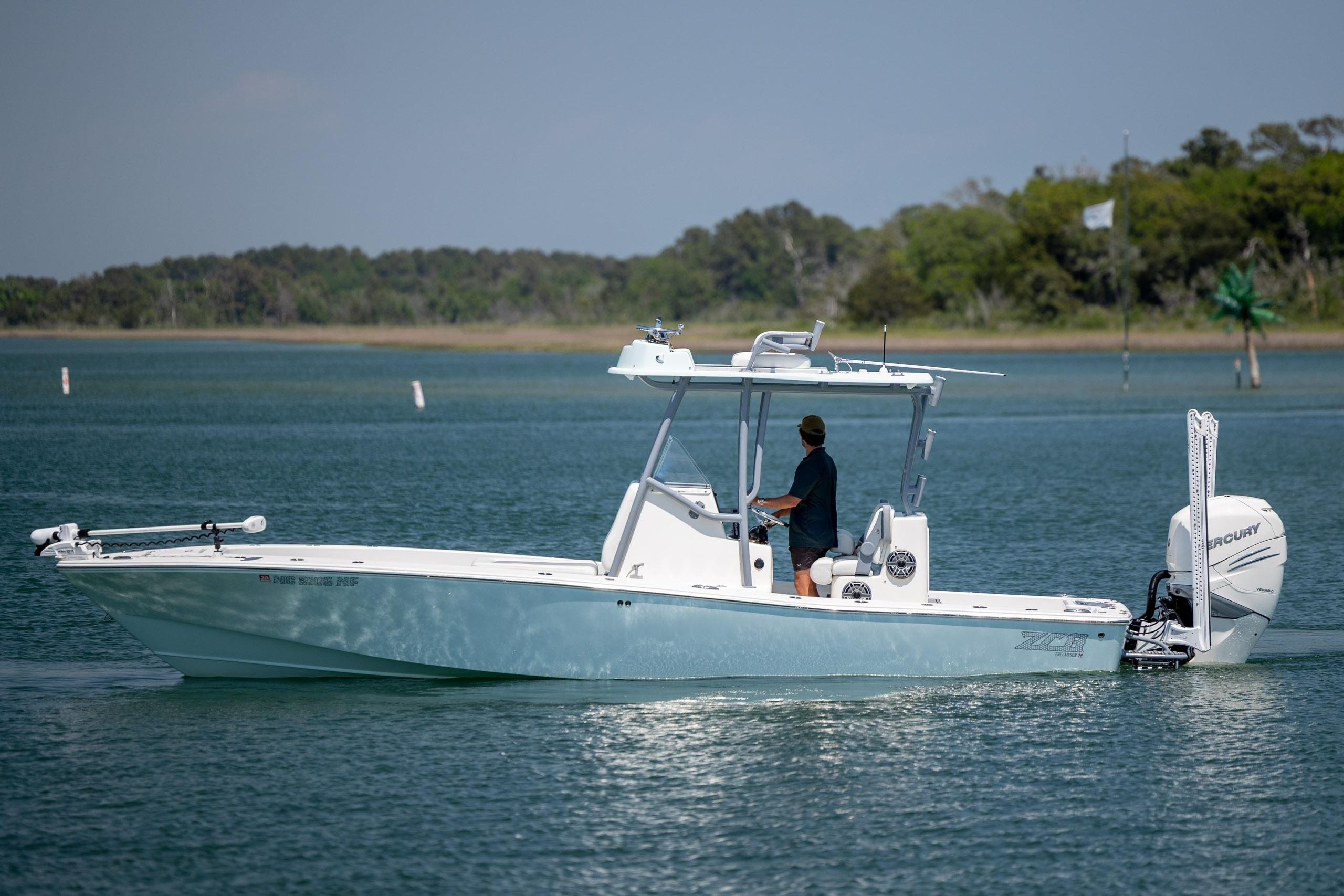 A 2022 ZCB Freemason 26 boat cruising on a calm lake with a person steering.