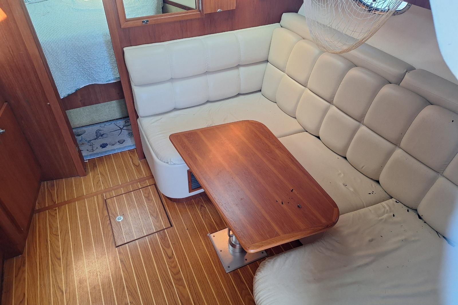 Interior of 2002 Tiara 3500 Open yacht with cushioned seating and wooden table.