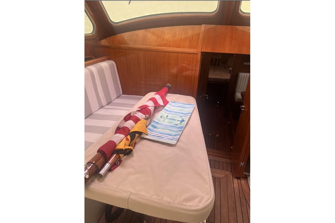 Interior of 2004 RB DERELI Daytripper 40 yacht with striped seating and folded flag.