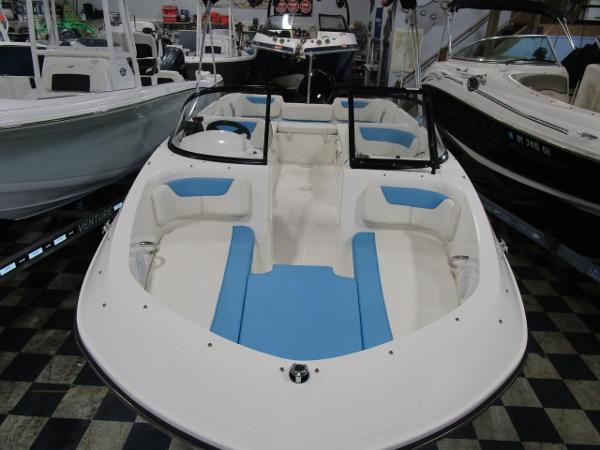 2023 Bayliner 210EL boat with blue and white interior, displayed in a showroom.