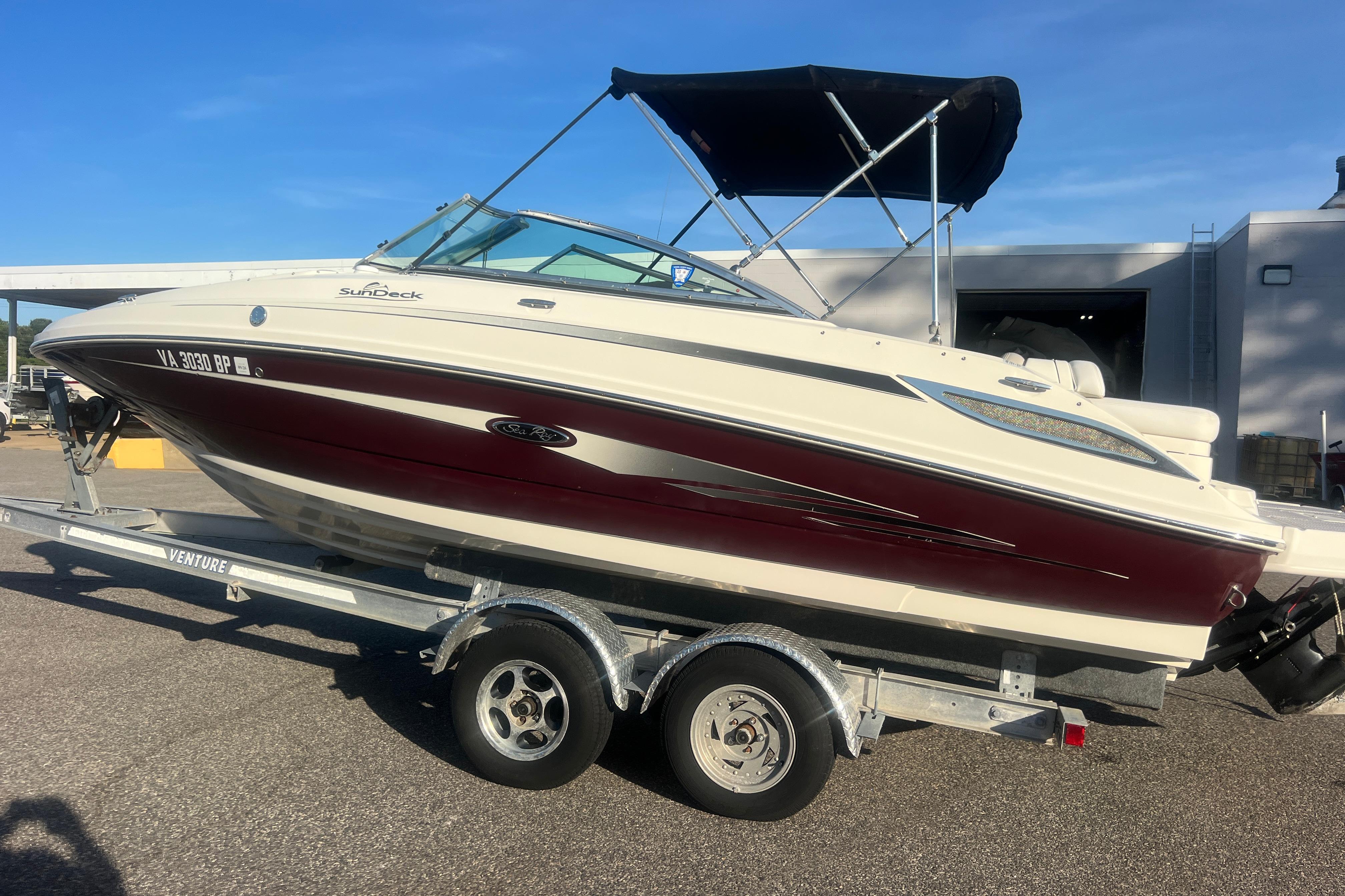 2009 Sea Ray 210 Sundeck boat on trailer, featuring maroon and white exterior.