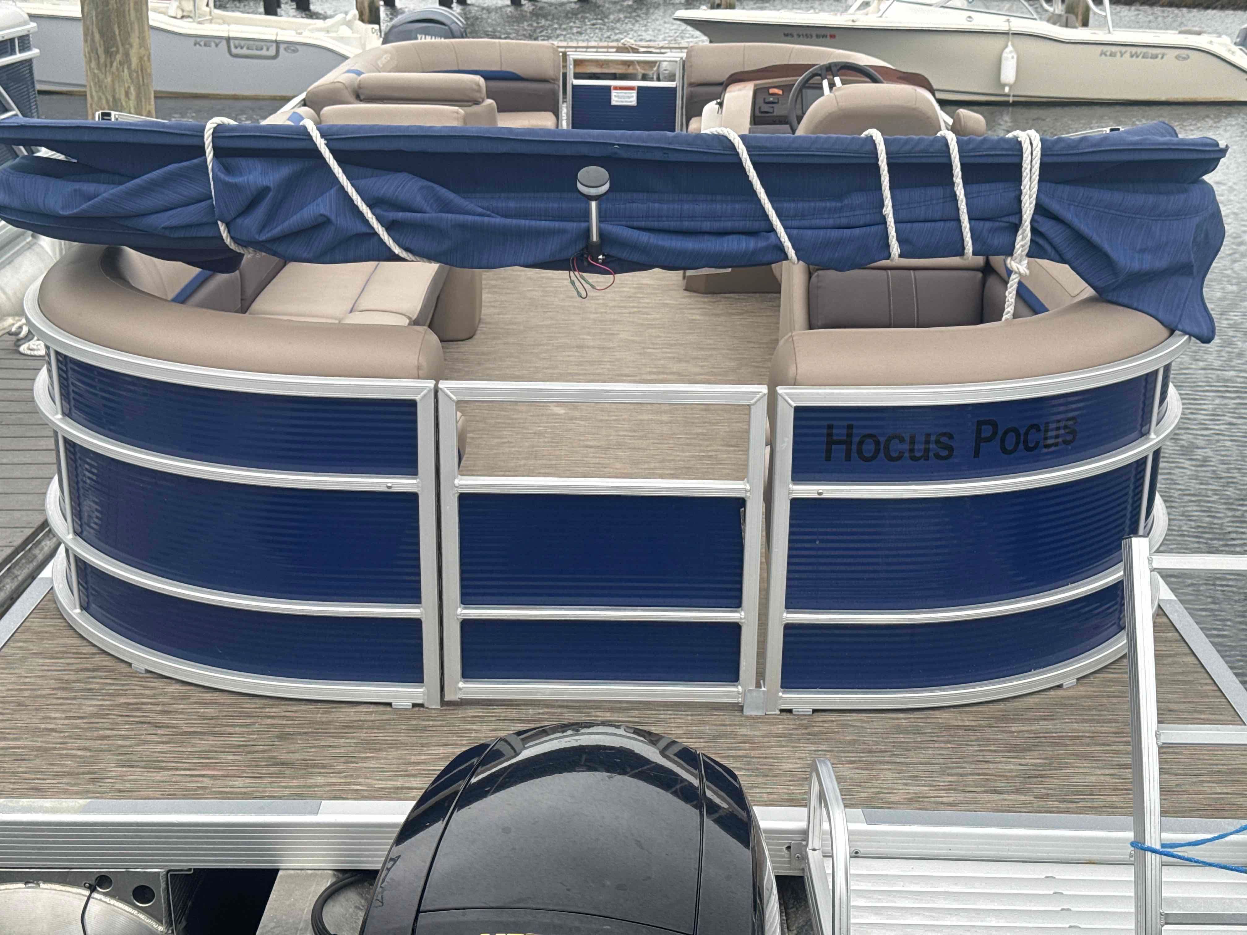 A Bennington 23SXSRC pontoon boat with blue and beige seating, docked at a marina.