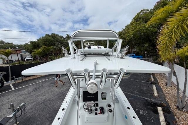 2025 Contender 26 Bay boat with advanced navigation equipment, docked near tropical foliage.