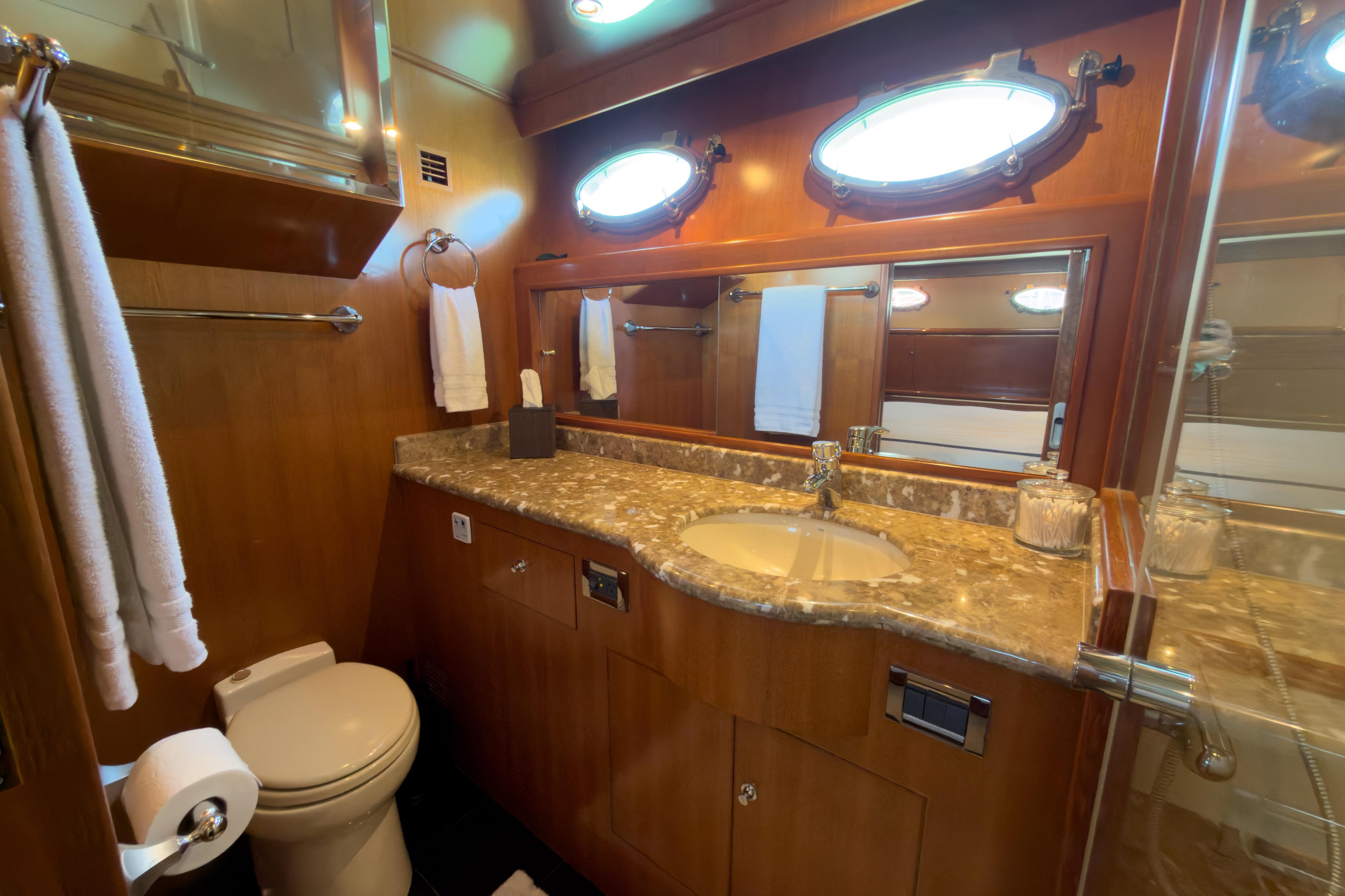 Luxurious bathroom in 2003 Ocean Alexander 700 Classicco yacht with marble countertop and porthole windows.