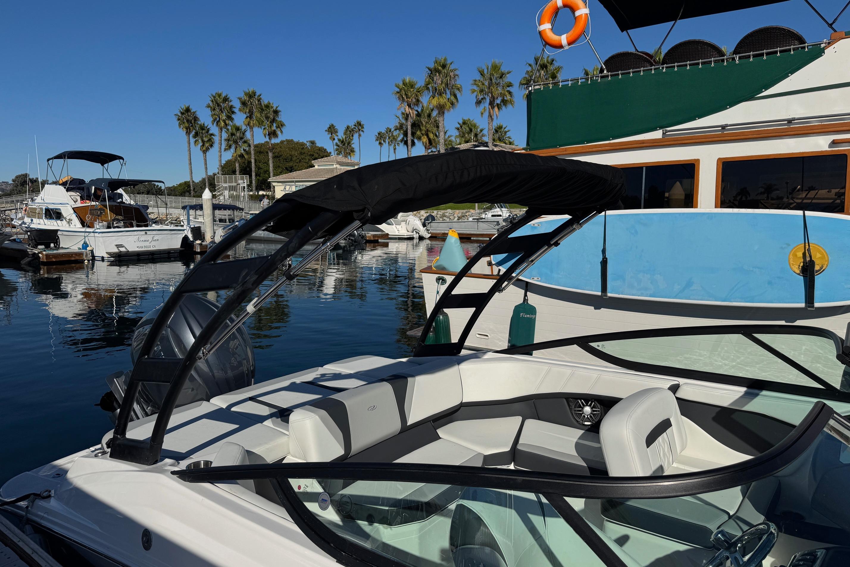 2026 Regal 21 OBX boat docked in a sunny marina with palm trees.