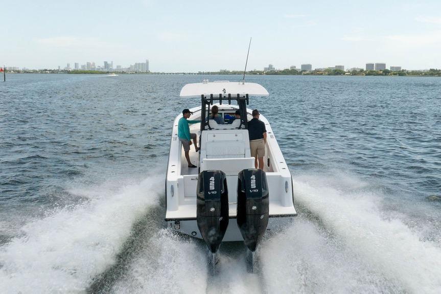 2027 Reef Runner 340 boat cruising on open water with city skyline in background.