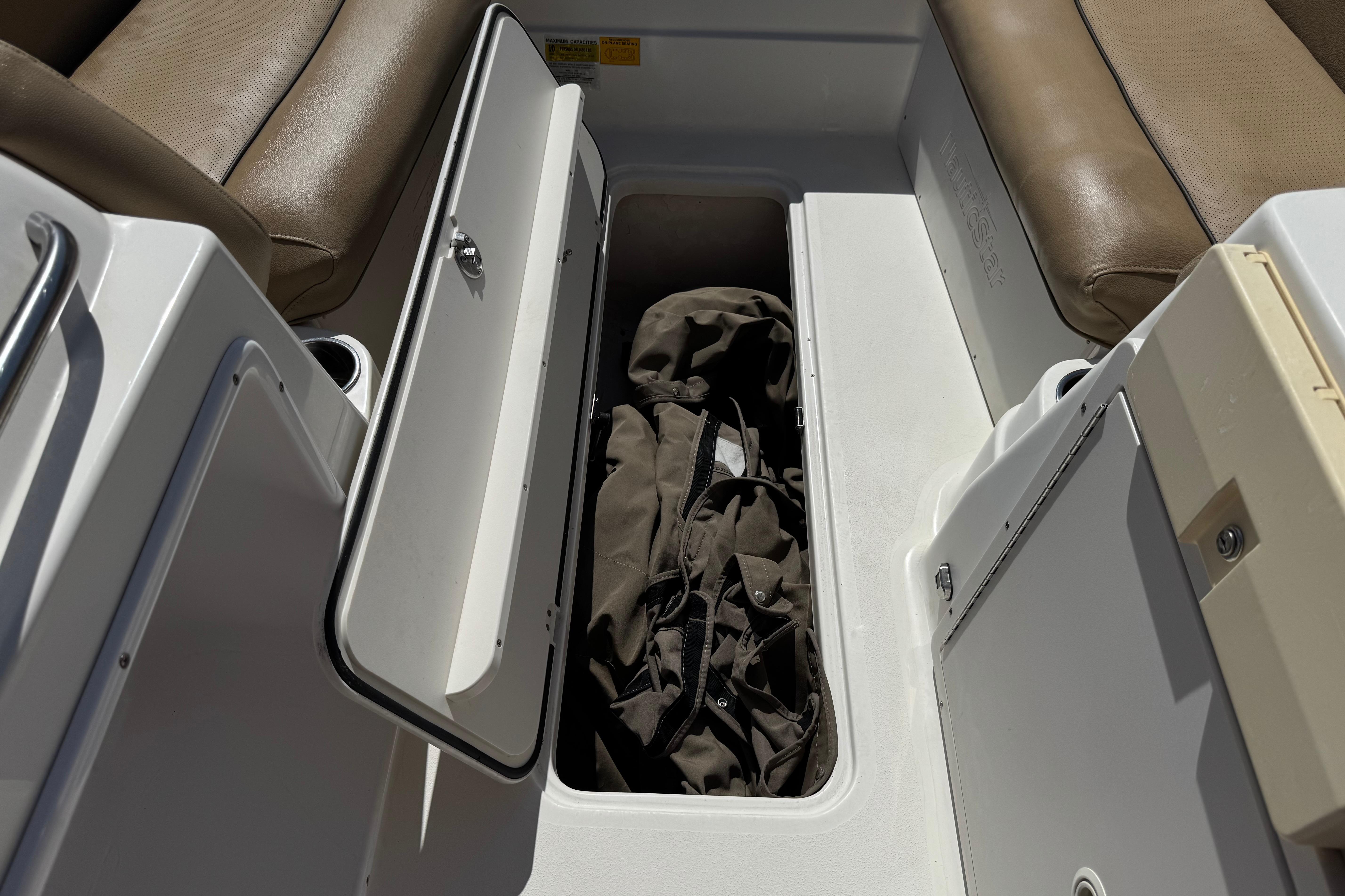 Open storage compartment on 2020 NauticStar 203 SC boat with brown seating.