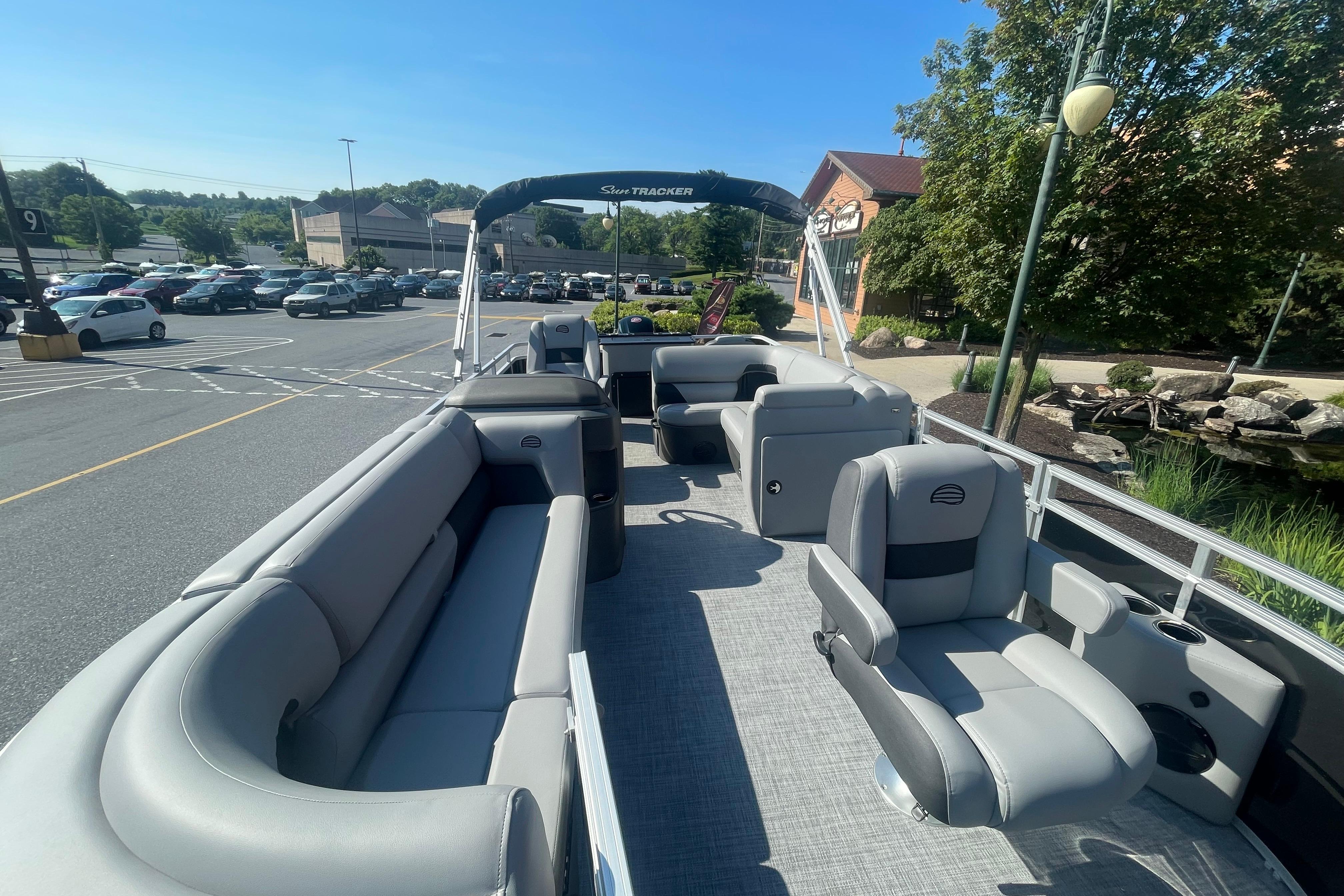 2026 Sun Tracker SportFish 20 DLX pontoon boat with spacious seating in a parking lot.