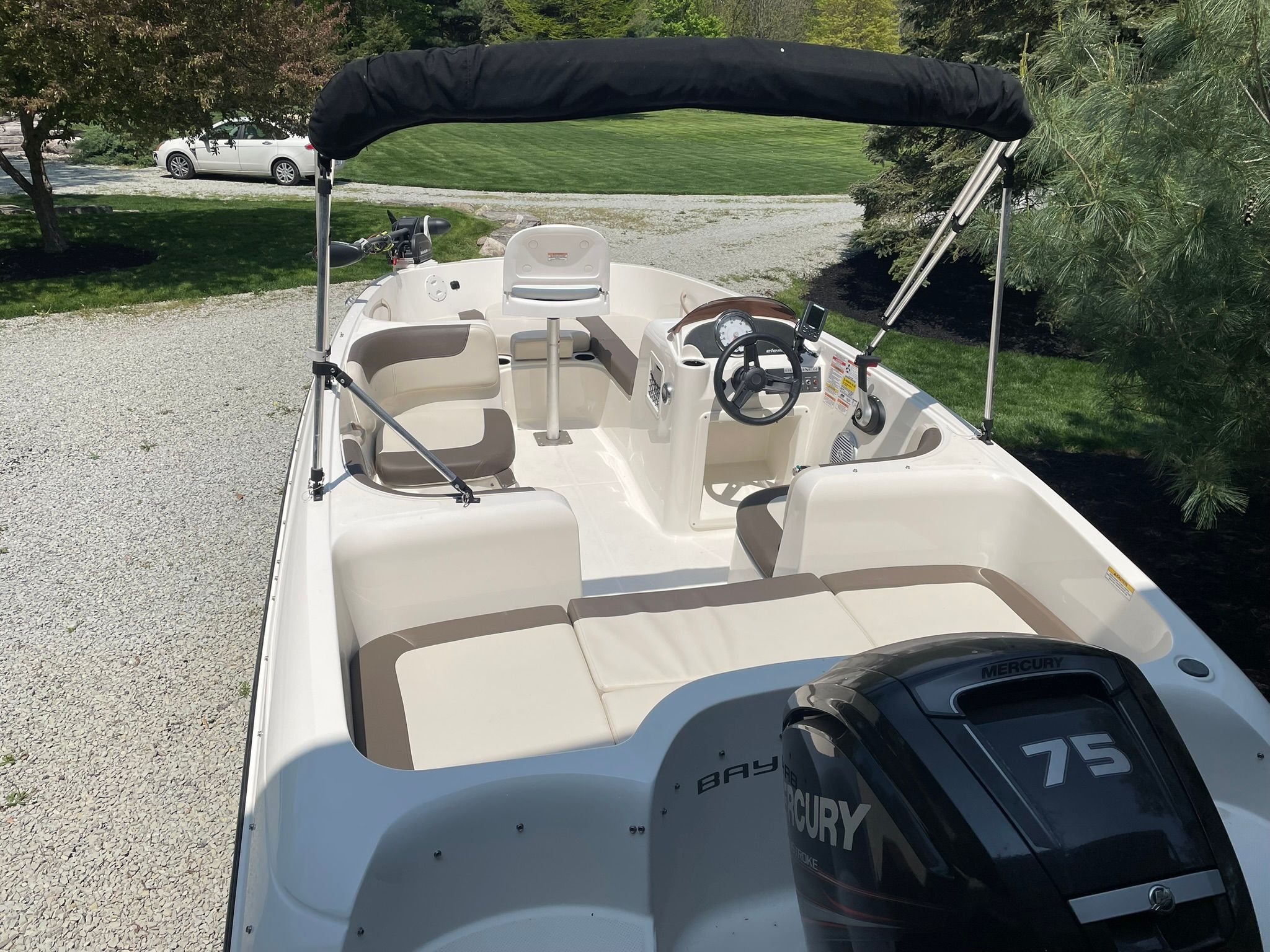 2018 Bayliner 160 Bowrider with open cockpit and Mercury 75 engine, parked on gravel.