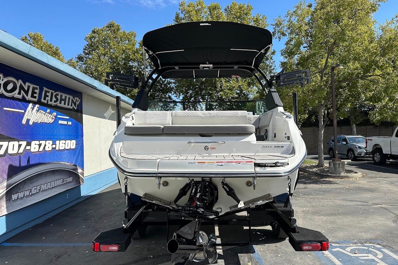 2026 Sea Ray SDX 230 Surf boat displayed outdoors, rear view, with trees and signage.
