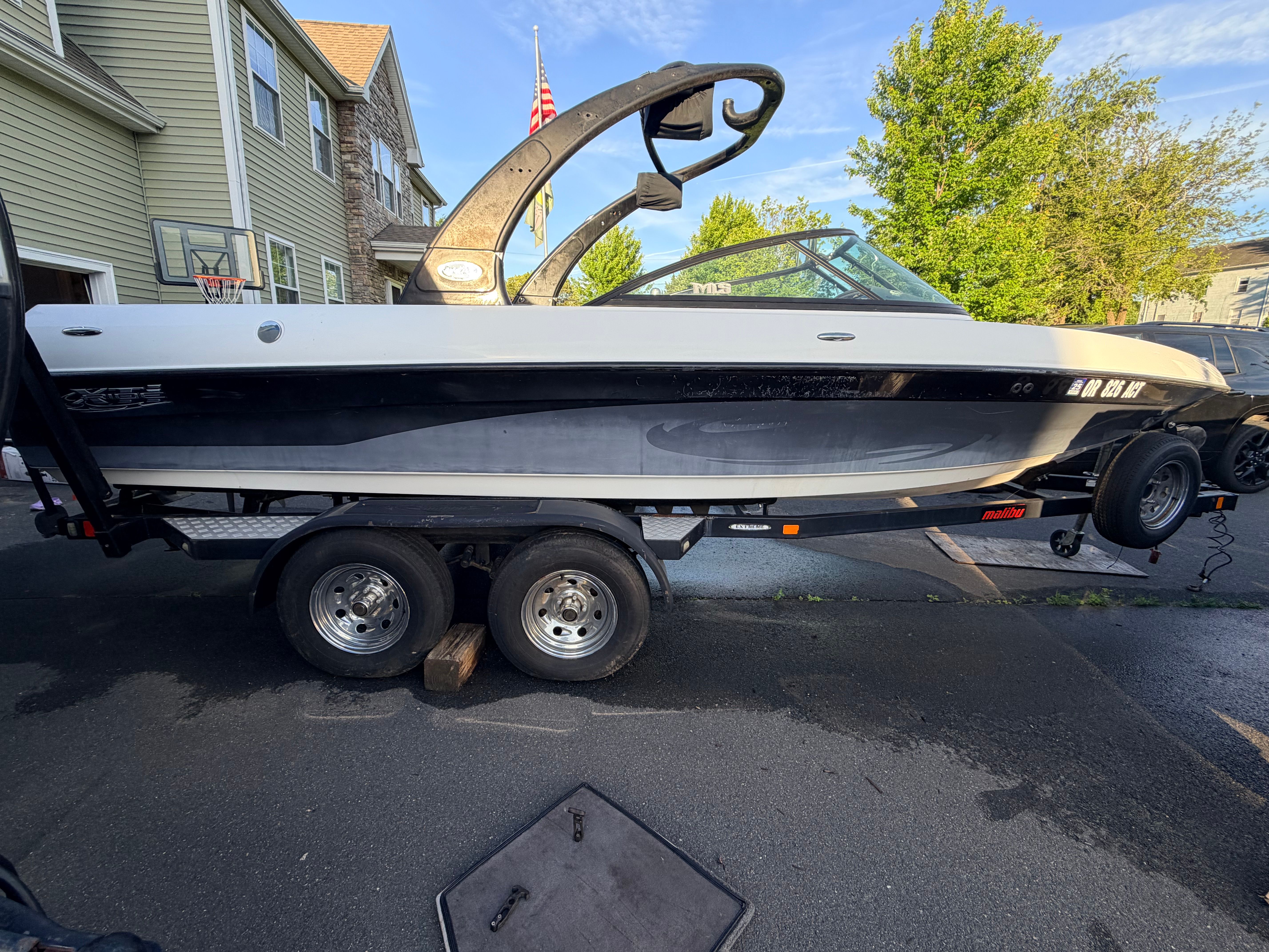 2006 Malibu iRide boat on trailer parked in driveway.