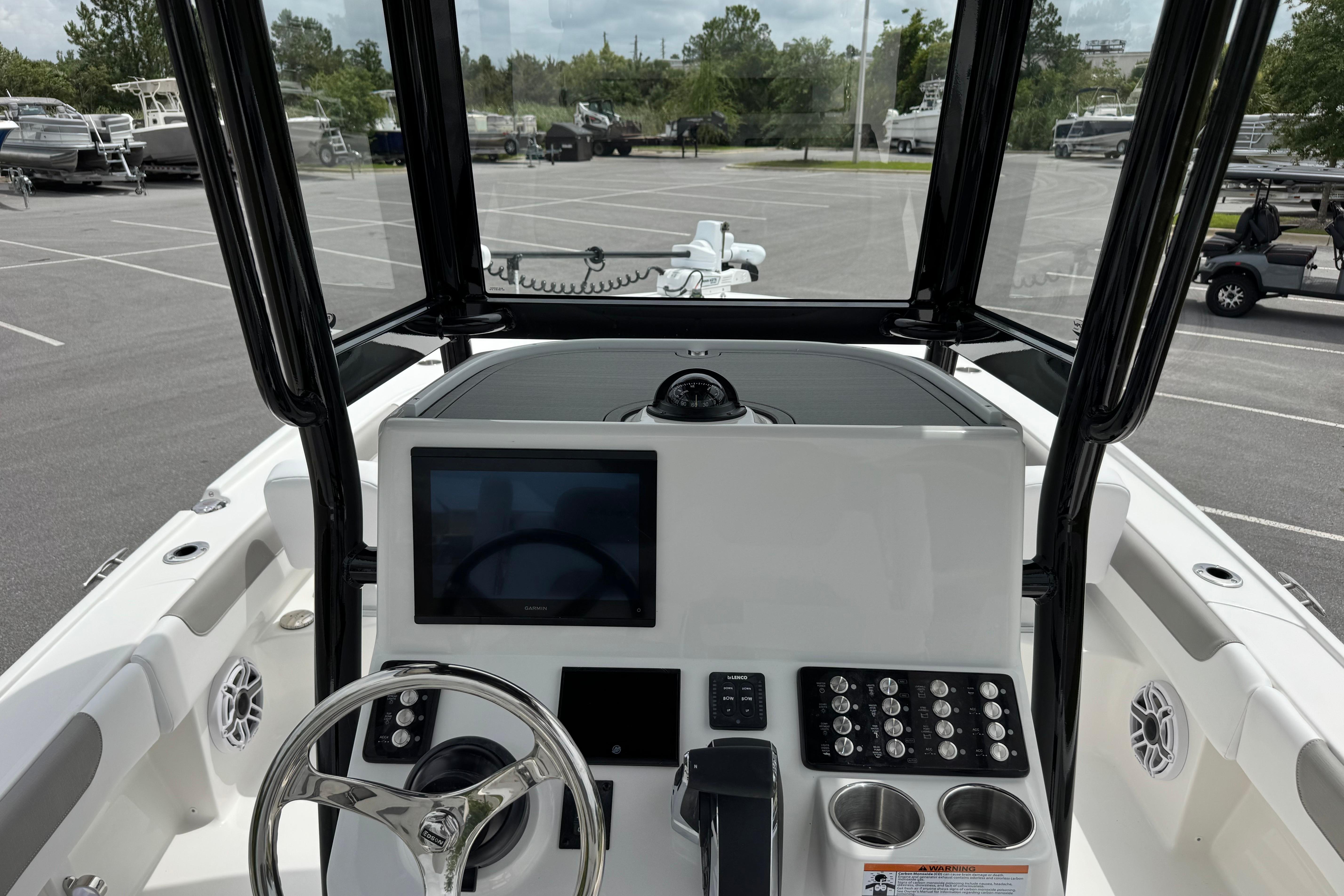 2027 Caymas 26 HB boat dashboard with steering wheel, touchscreen, and control panel in a parking lot.