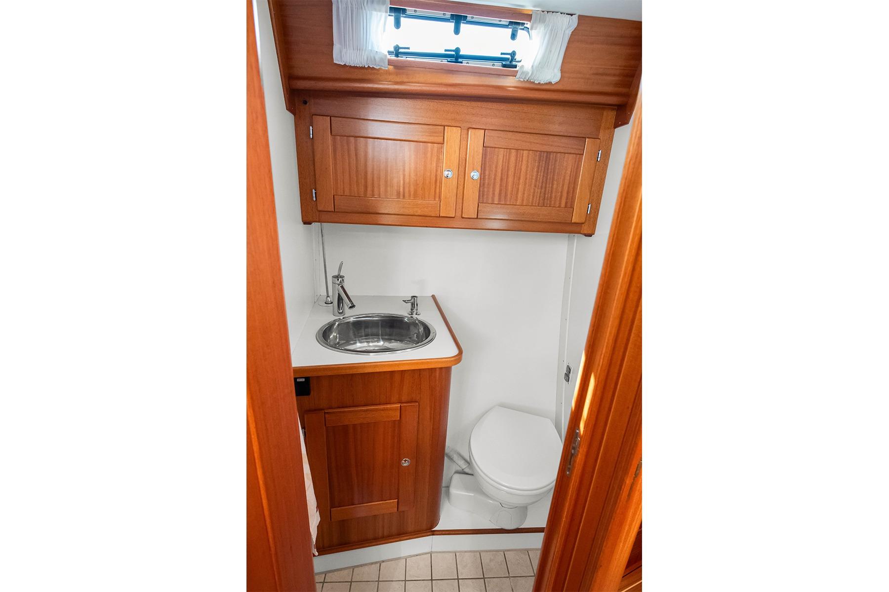 Compact bathroom in 2007 Nordship 40 DS yacht with wooden cabinetry and stainless steel sink.