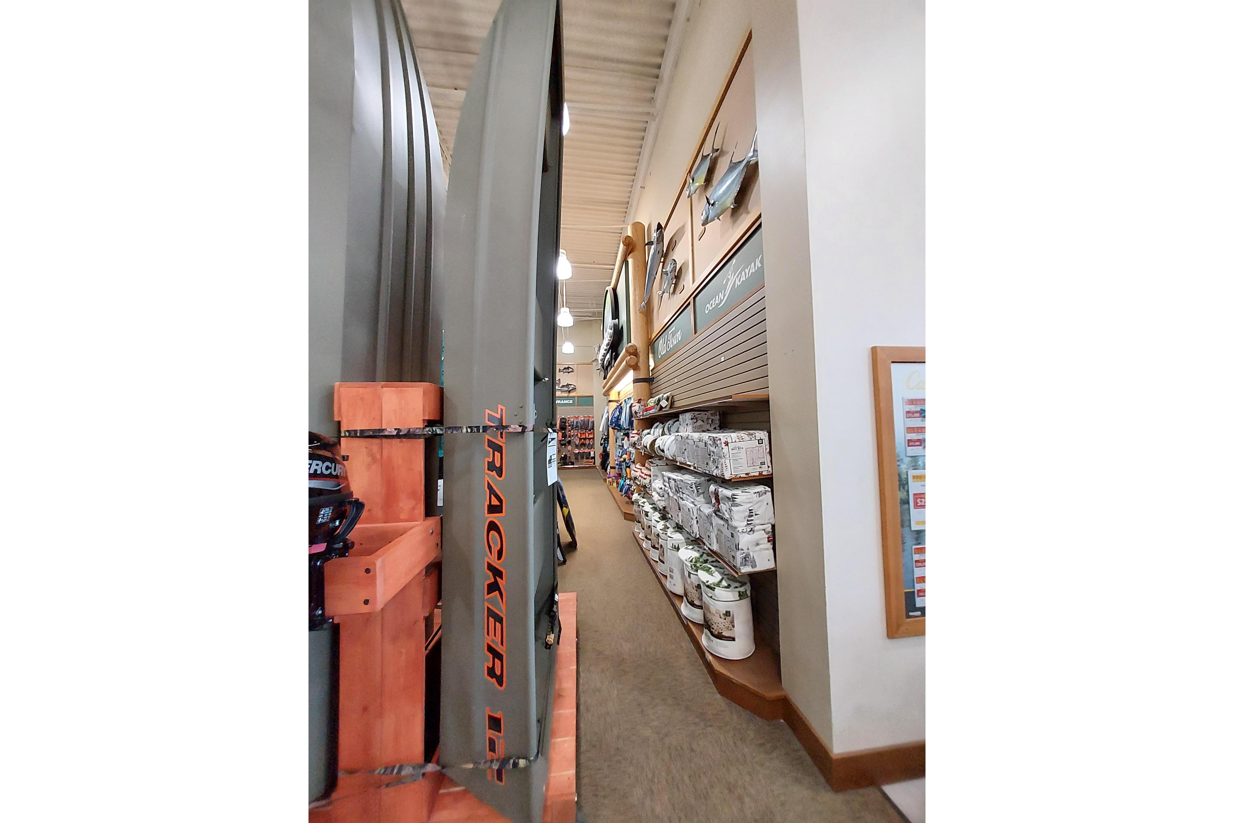 2025 Tracker Grizzly 1236 Utility boat displayed in a store aisle with fishing gear.