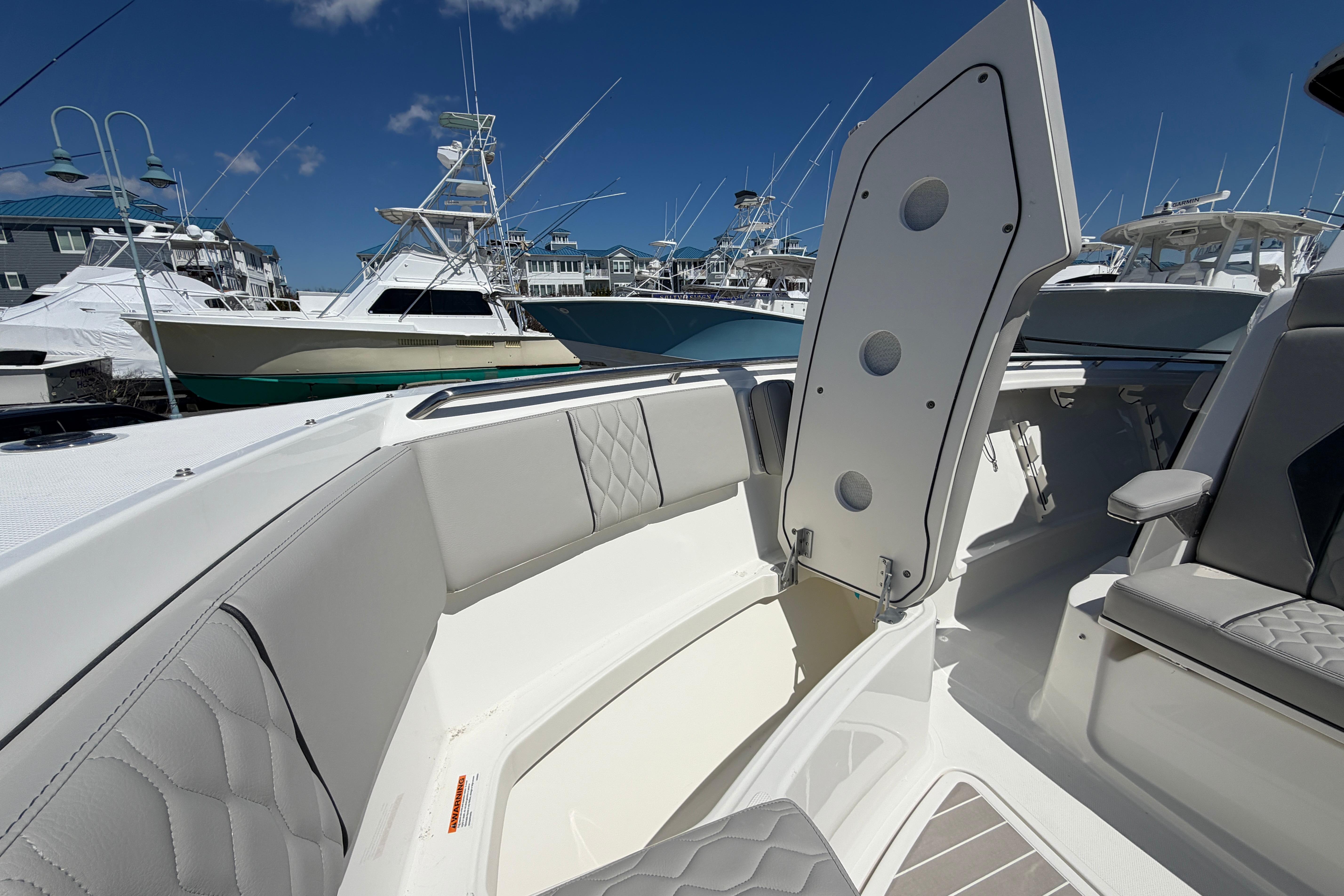 2026 Pursuit S 358 Sport boat interior with open storage compartment, docked among other boats.